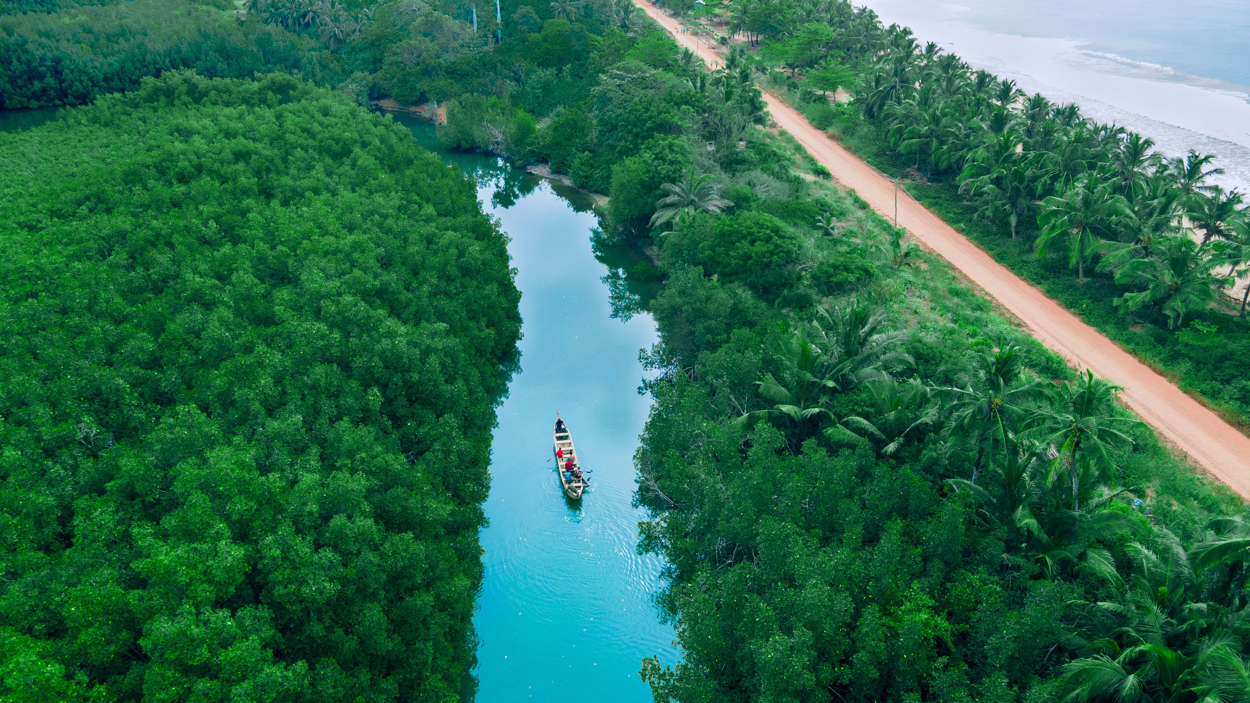 A boat sails through a lush green river.