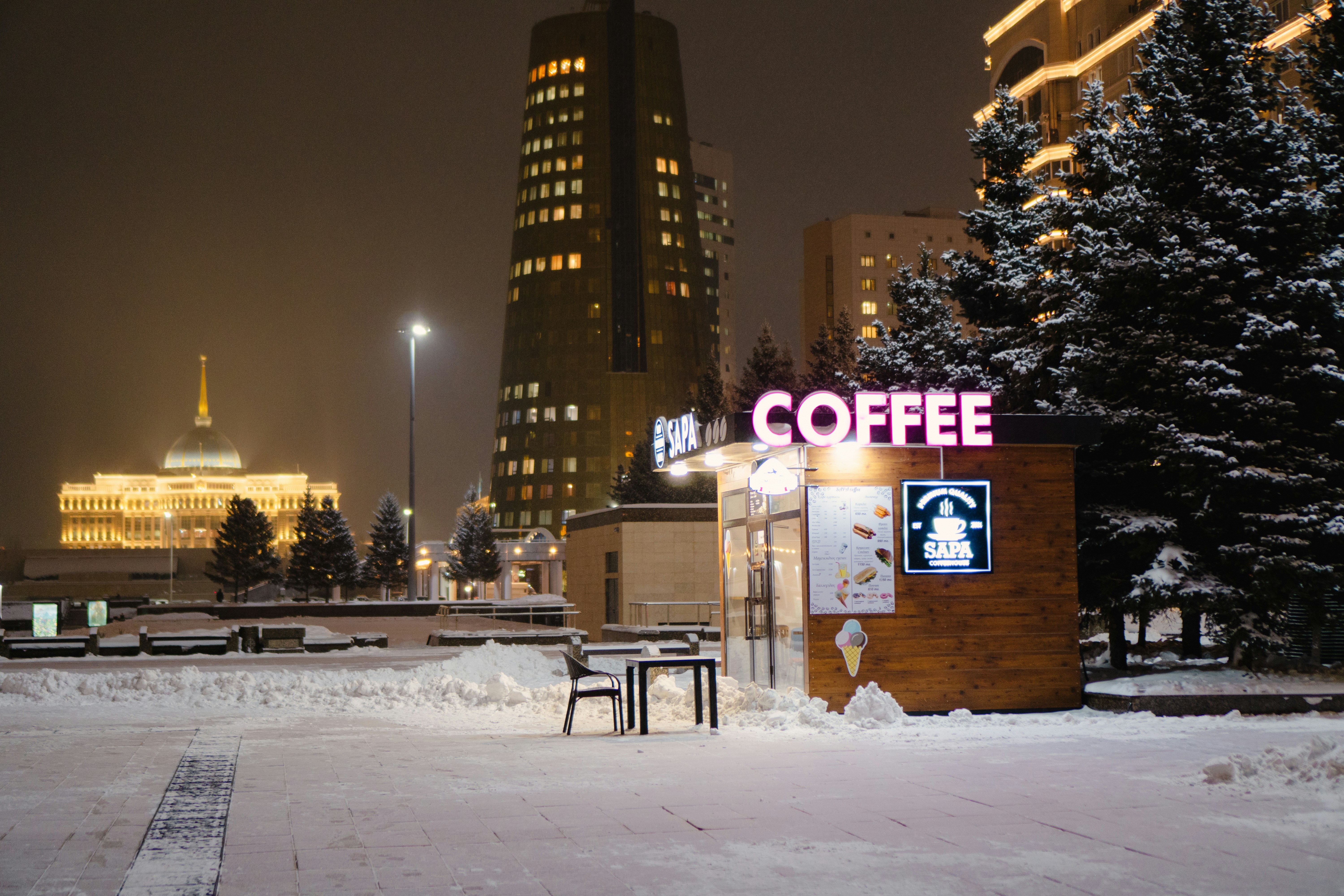 A coffee shop sits amidst a snowy night.