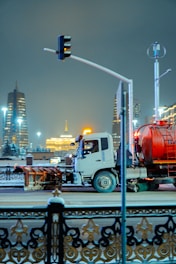 A truck drives down a snowy city street at night.