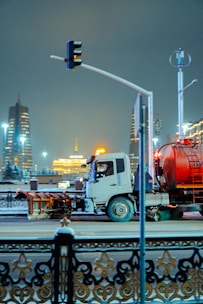 A truck drives down a snowy city street at night.
