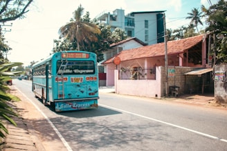 A blue bus drives down a sunny sri lankan road.