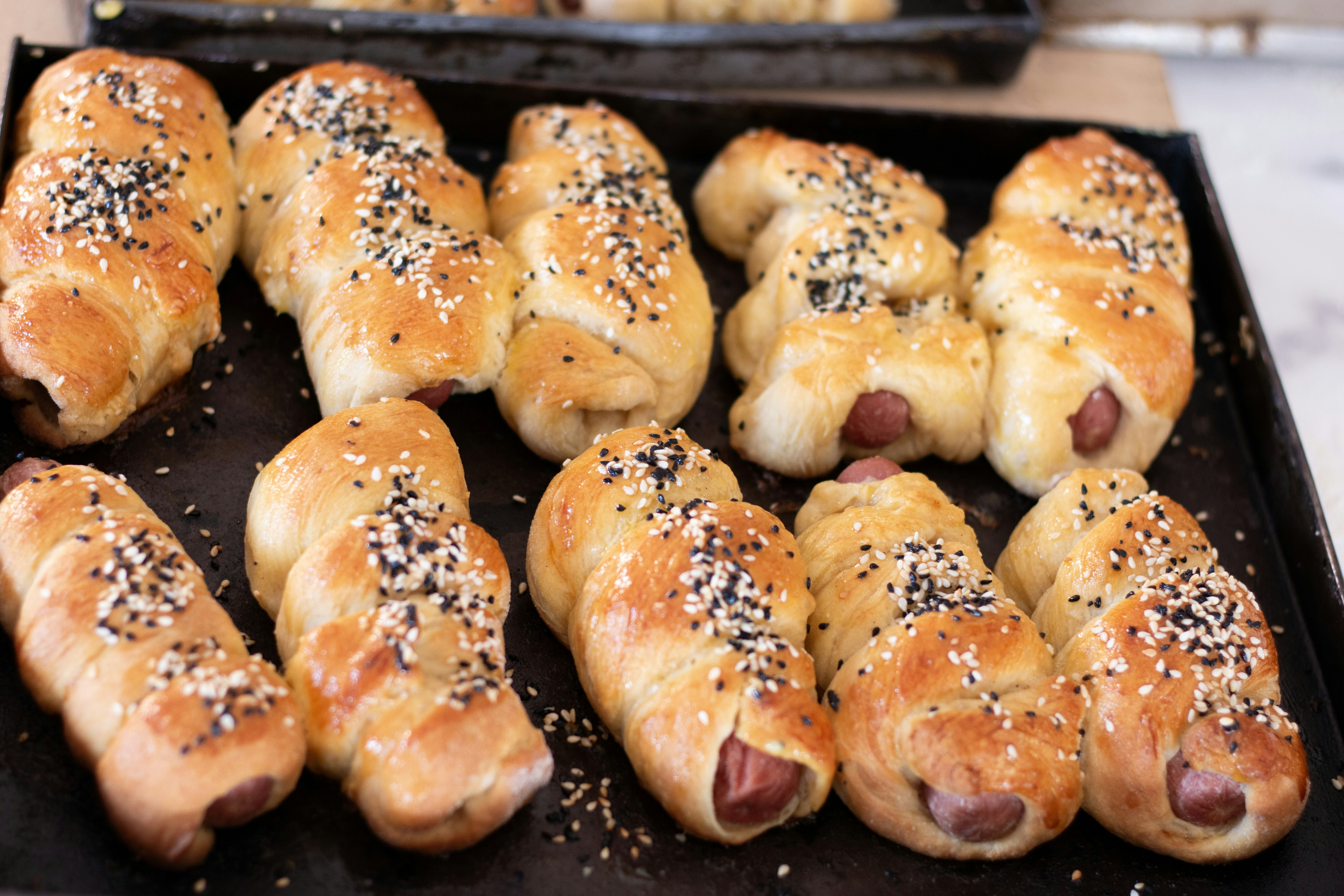 Delicious sausage rolls are on a tray.