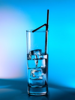 Glass of water with ice and a straw.