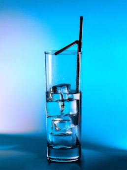 Glass of water with ice and a straw.