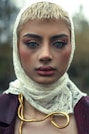 A woman is wearing a headscarf, looking sad.