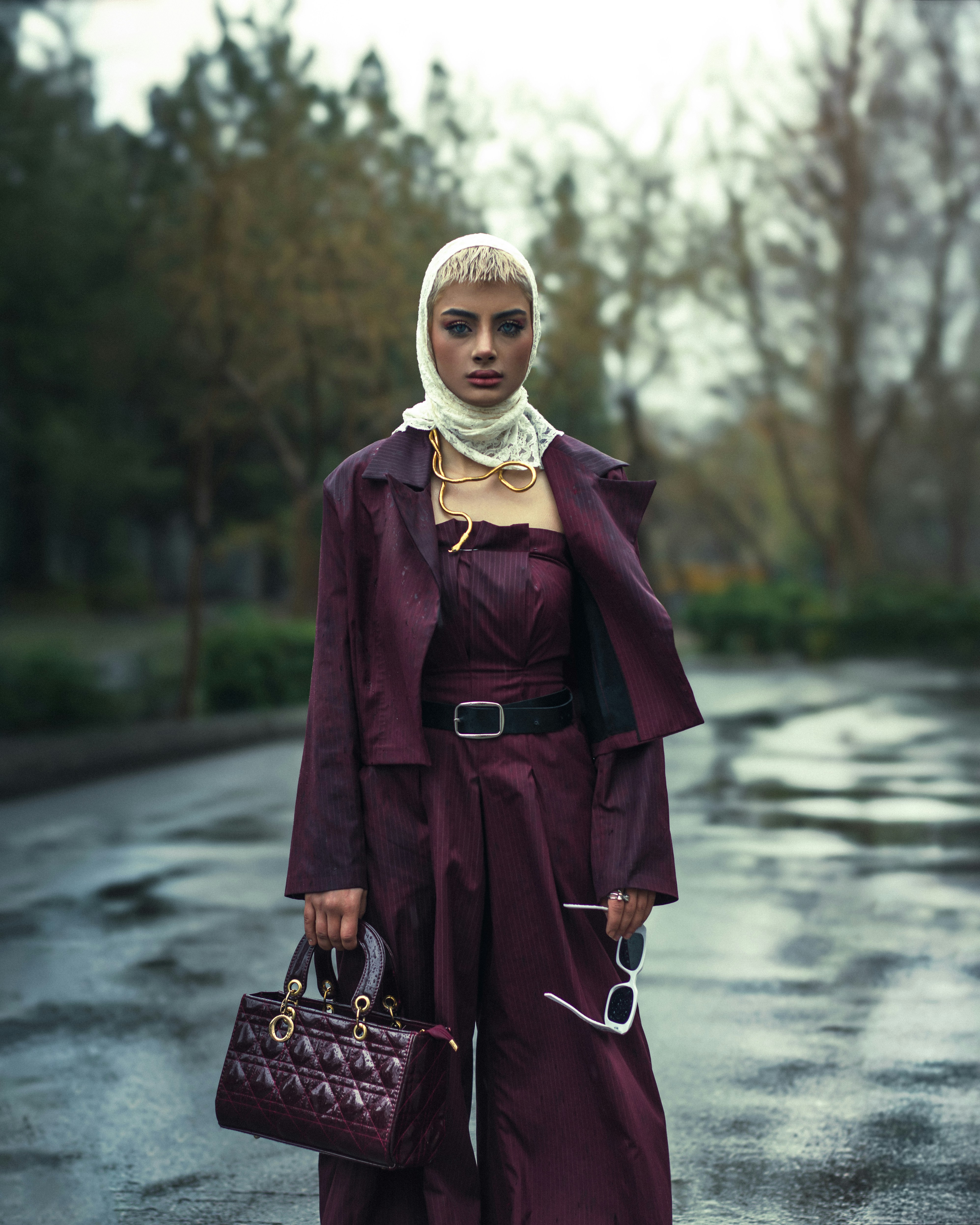 Fashionable woman in burgundy outfit poses outside.