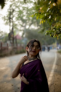 Woman in a saree poses on a road.