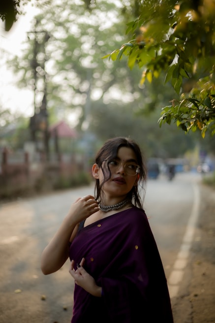 Woman in a saree poses on a road.