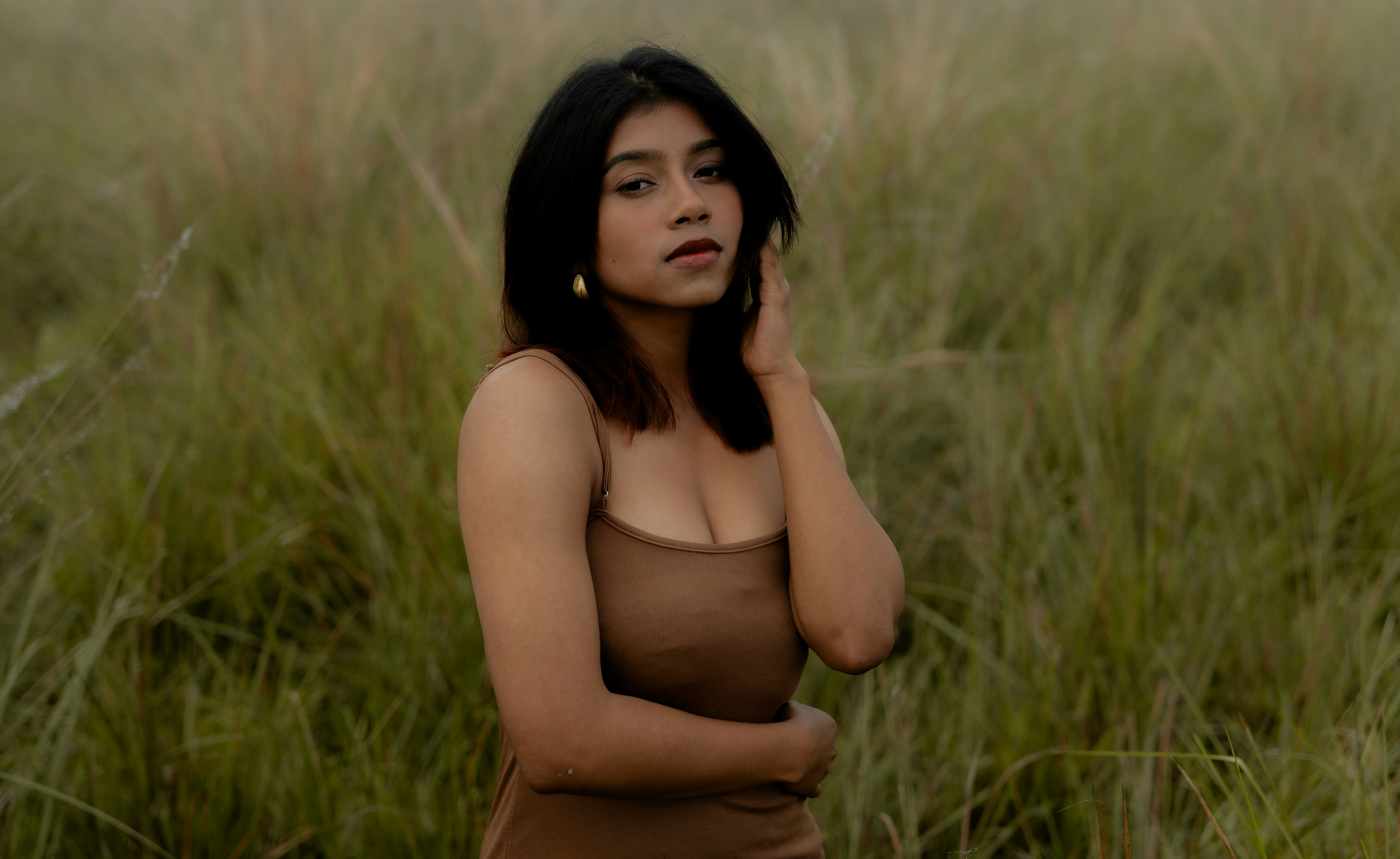 A woman poses in a field of tall grass.