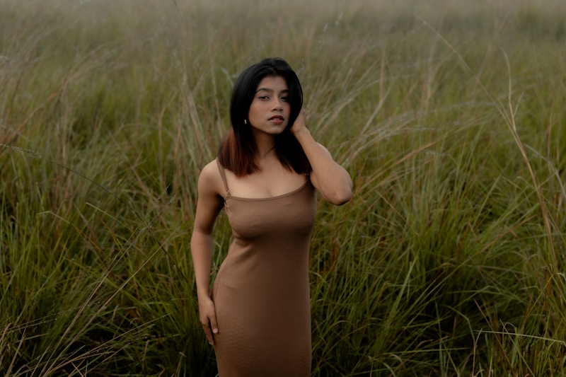 A woman poses in a field of tall grass.