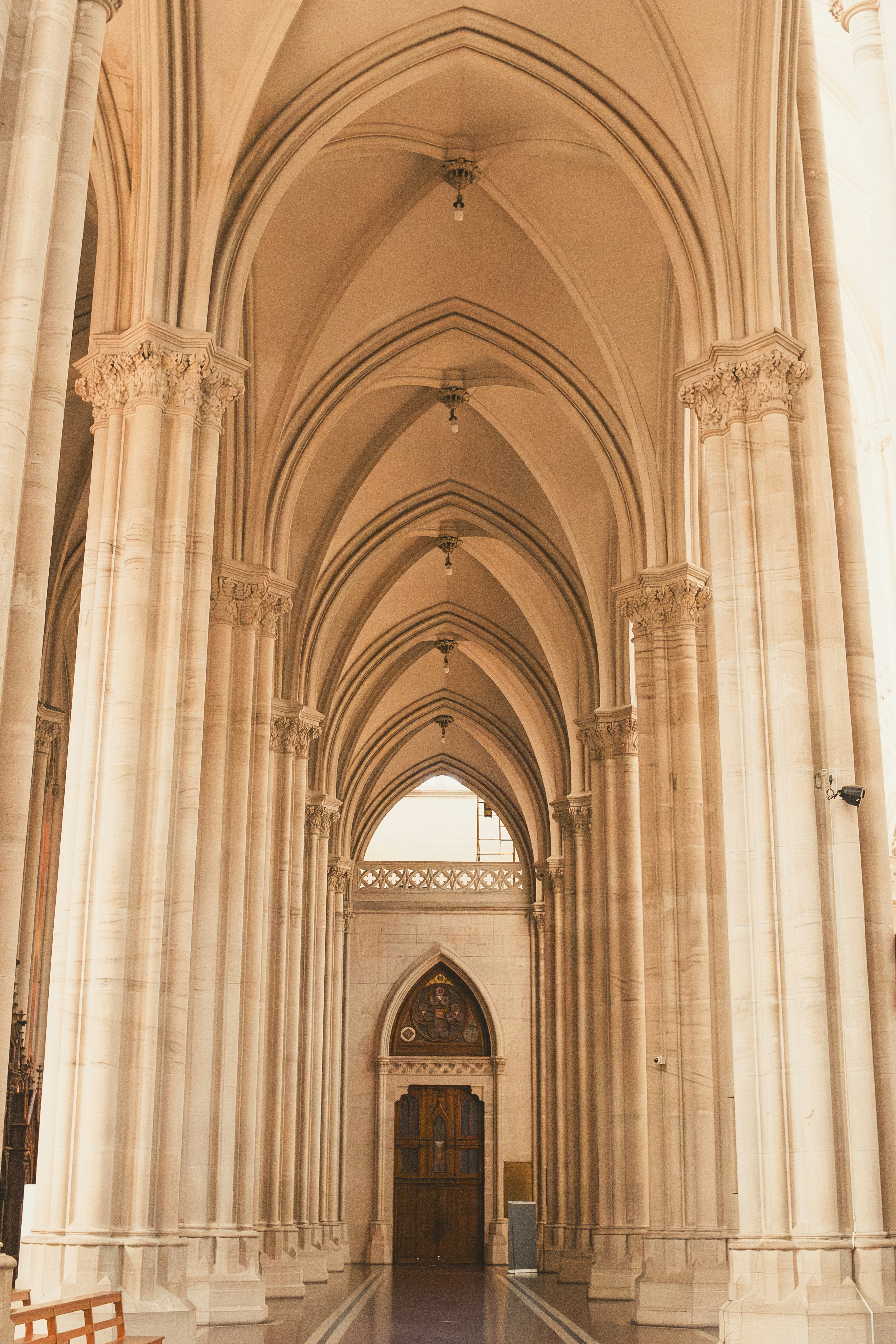 Arched corridor with detailed columns leads to a door.