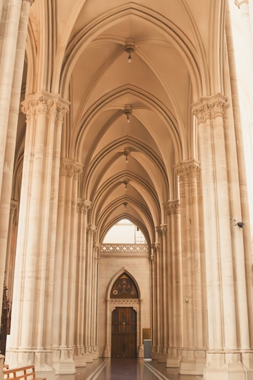 Arched corridor with detailed columns leads to a door.