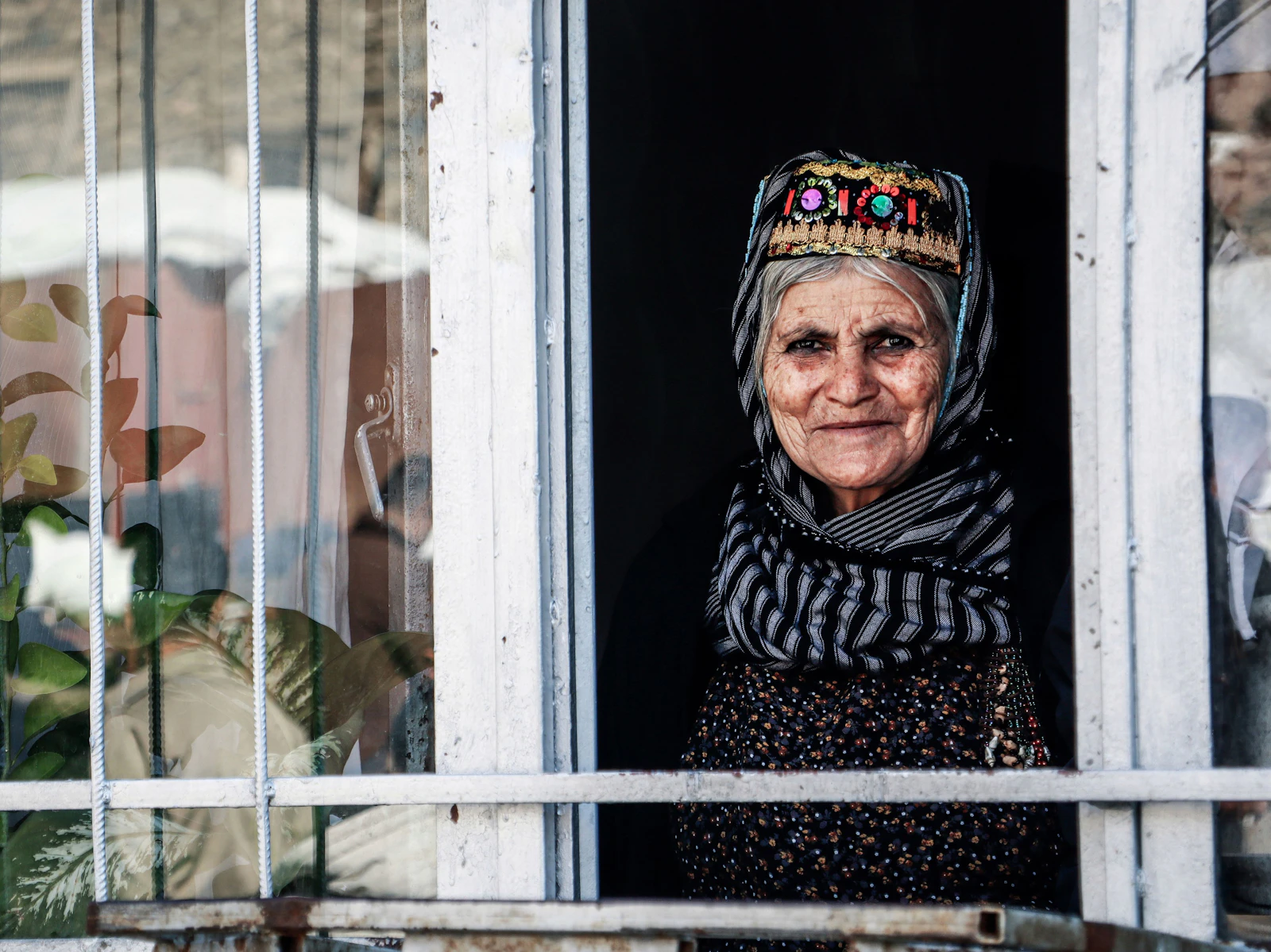An elderly woman looking out from the window of her home