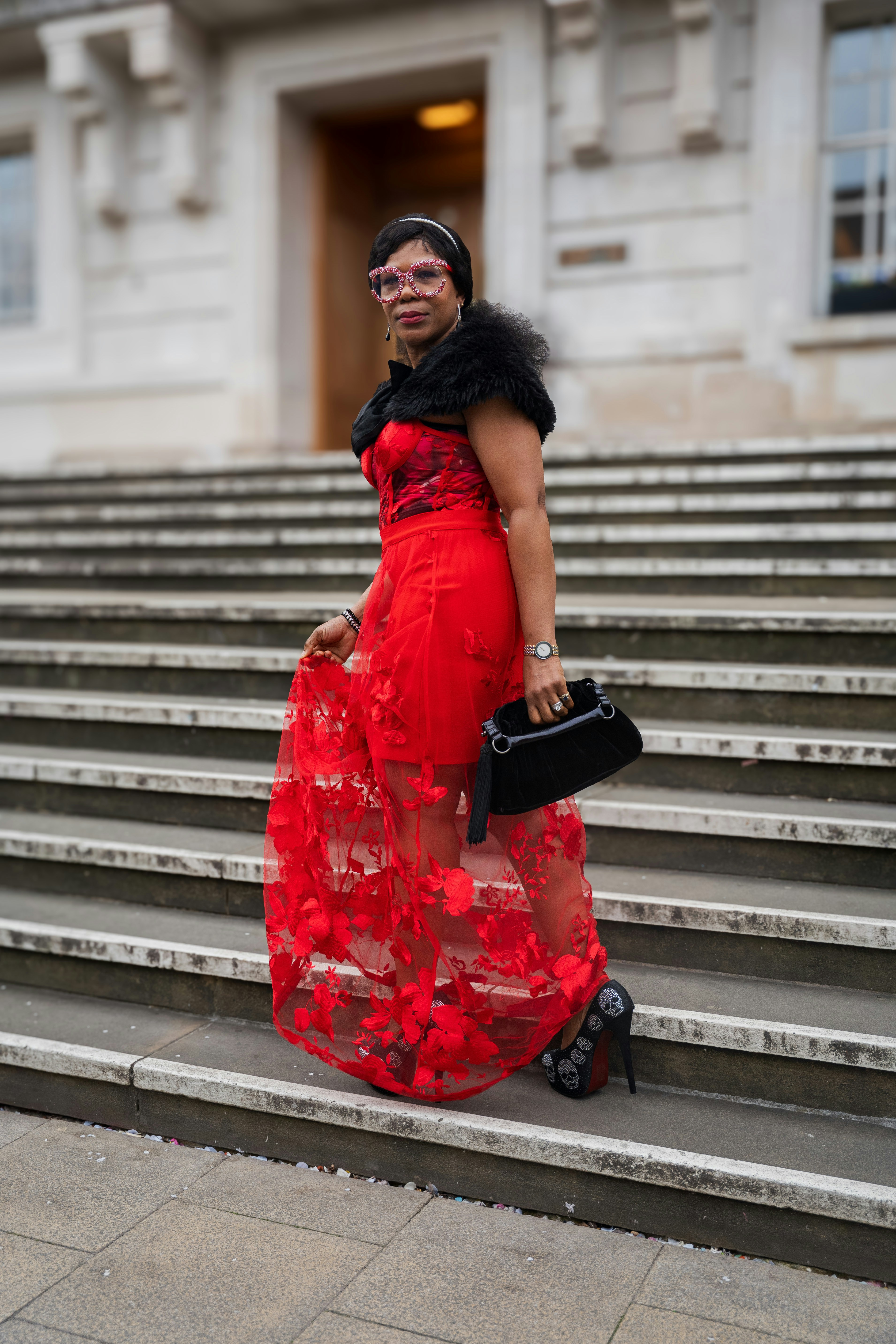 Woman in red dress poses on steps.