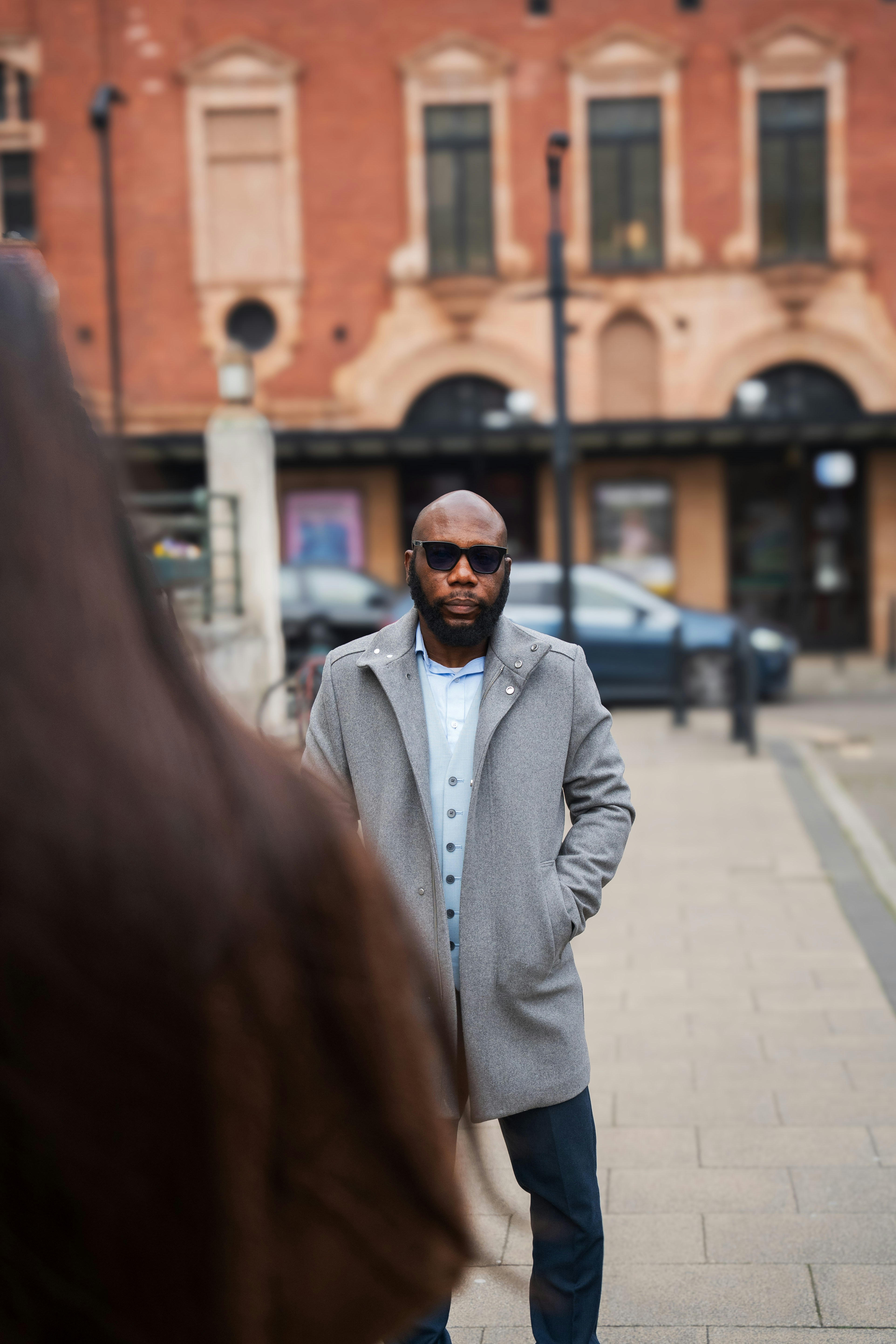 Stylish man poses in front of a building.