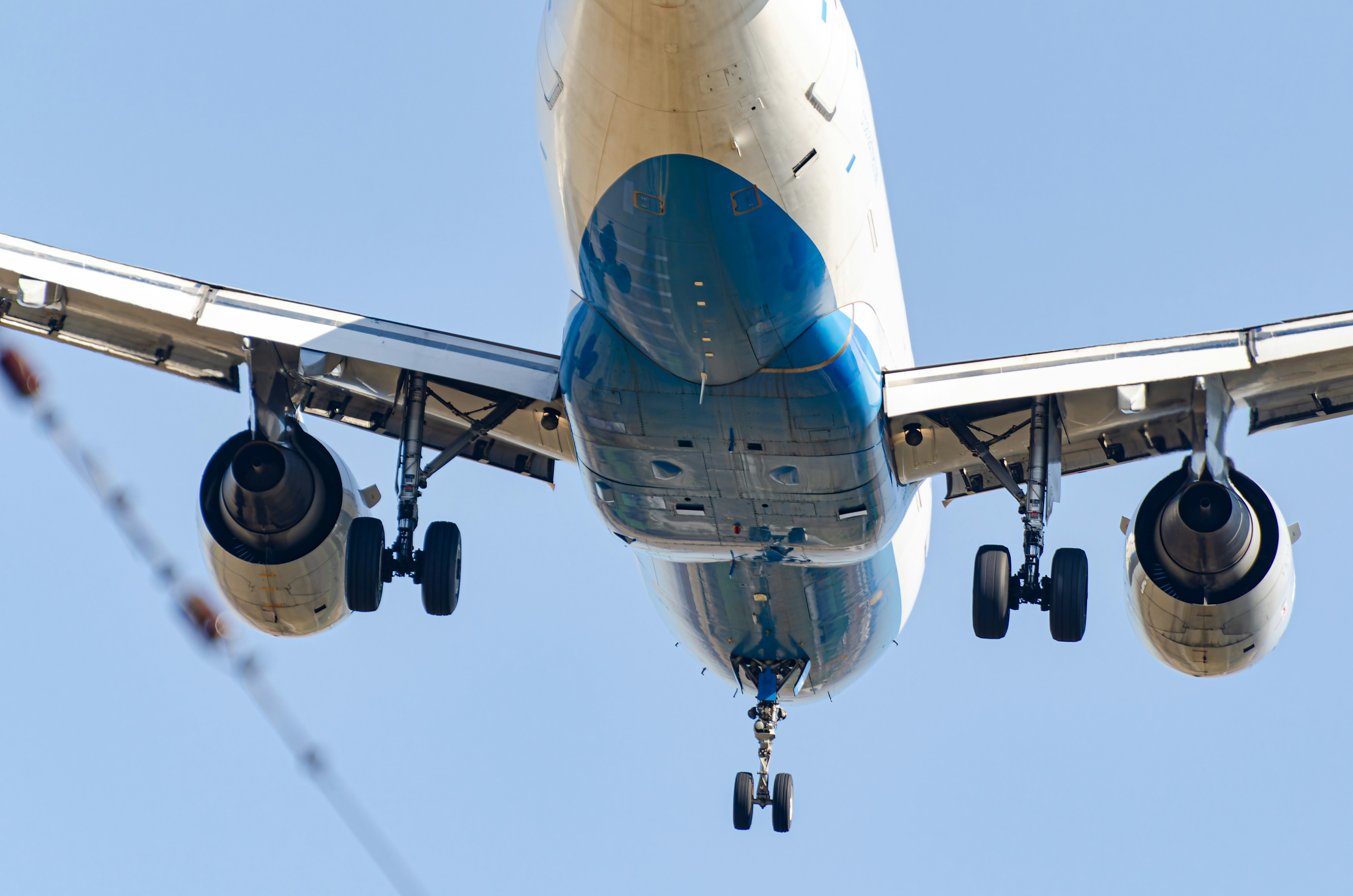 Airplane underside in mid-air with landing gear.