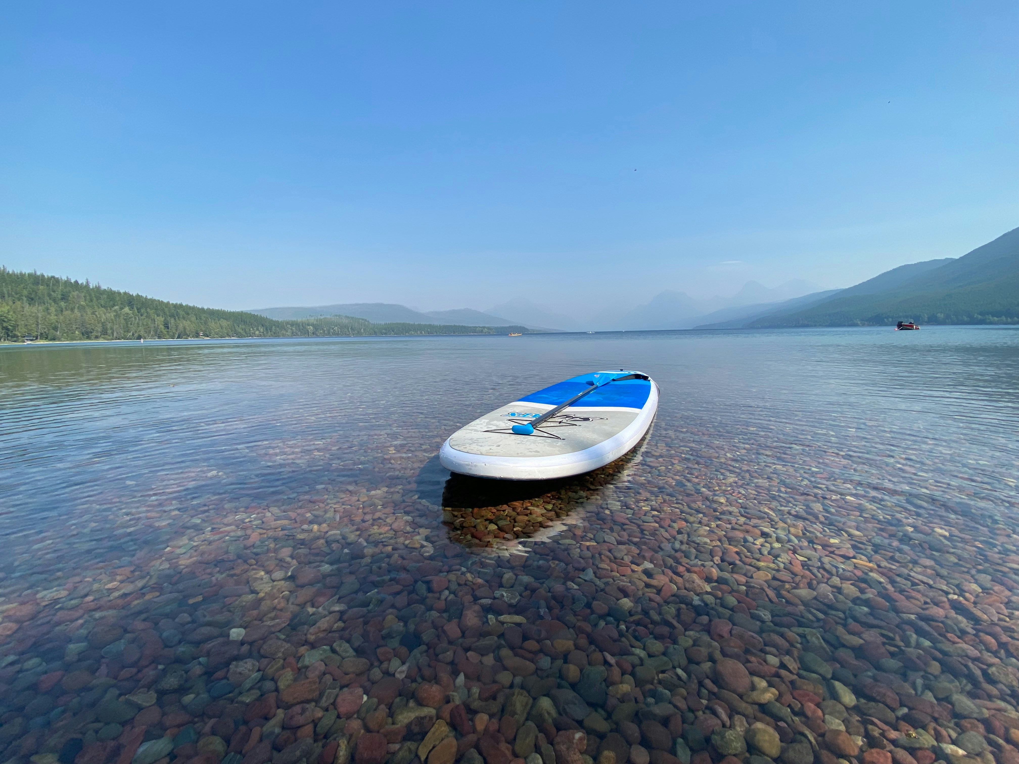 A paddleboard floats serenely on a clear lake.
