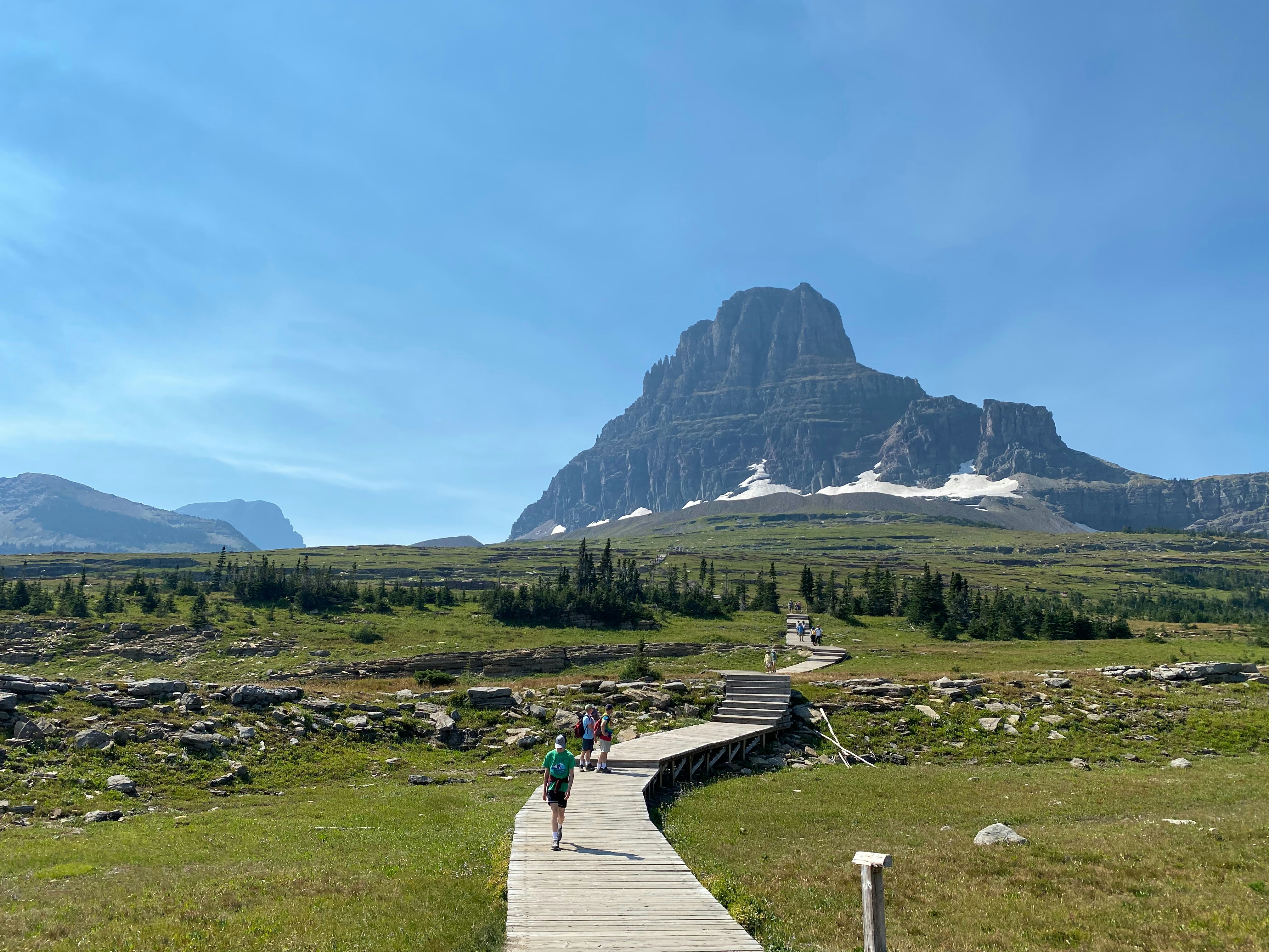 A wooden walkway leads towards a mountain.