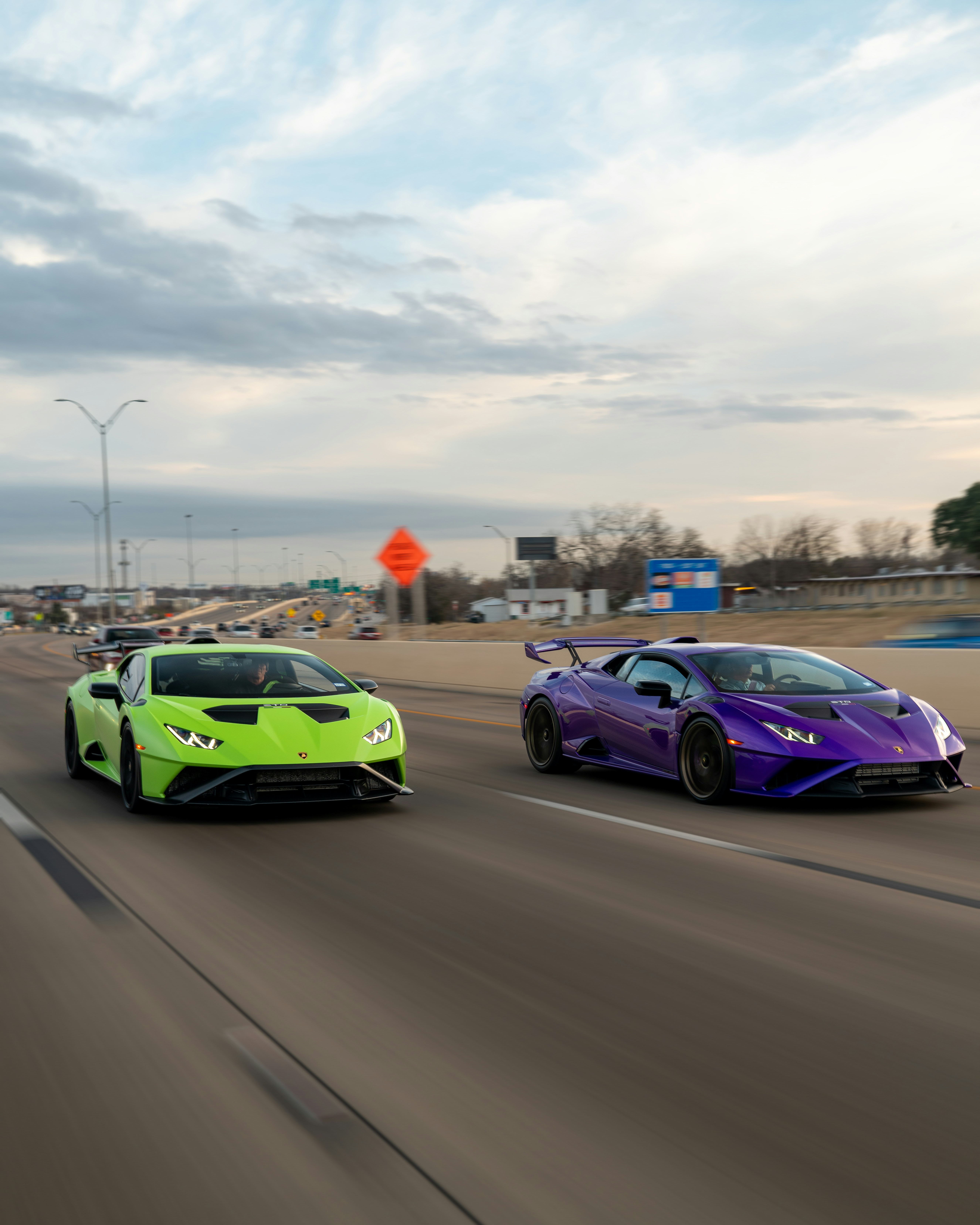 Neon green and purple sports cars speed along an elevated highway.