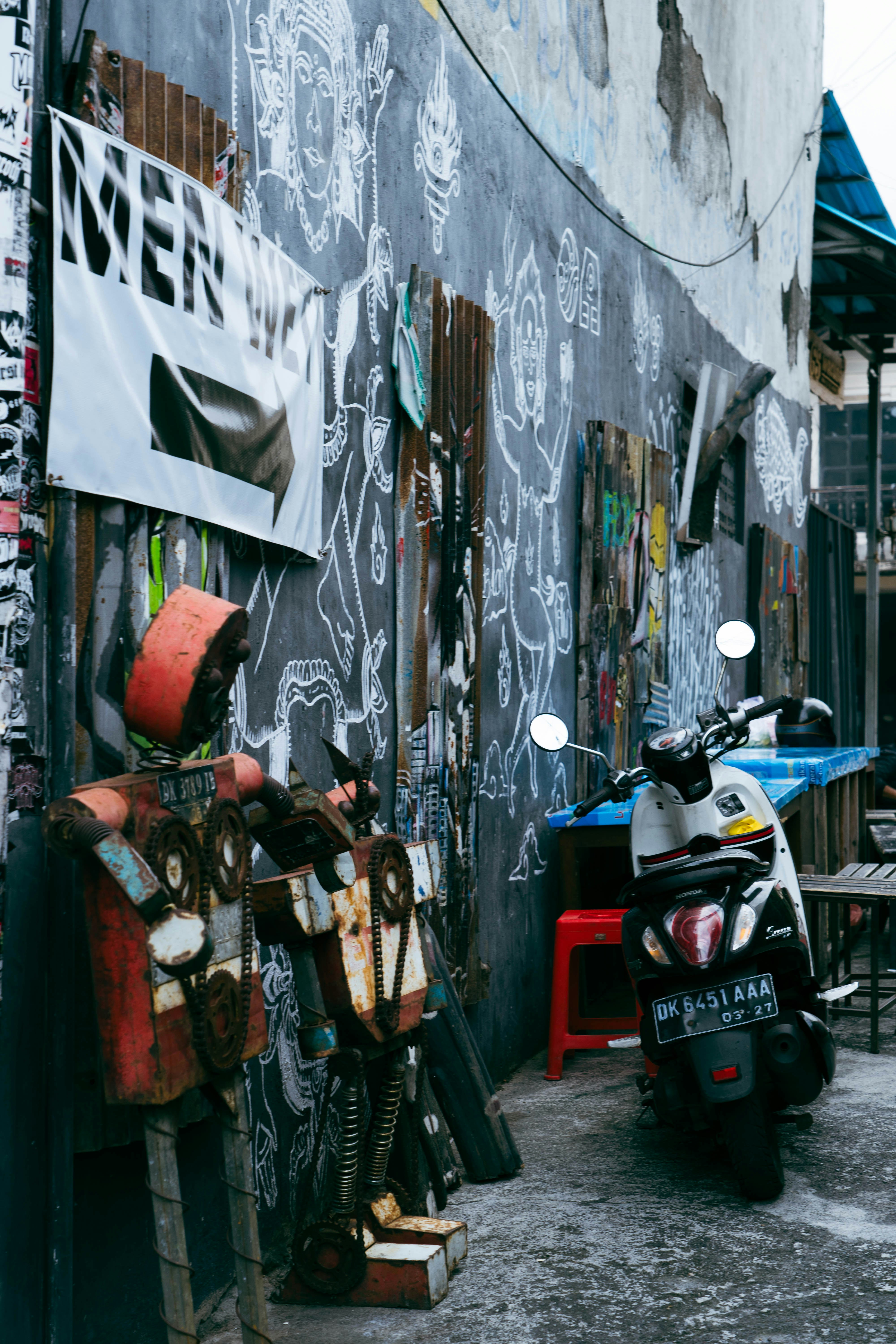 Street art and a scooter decorate a weathered alley.