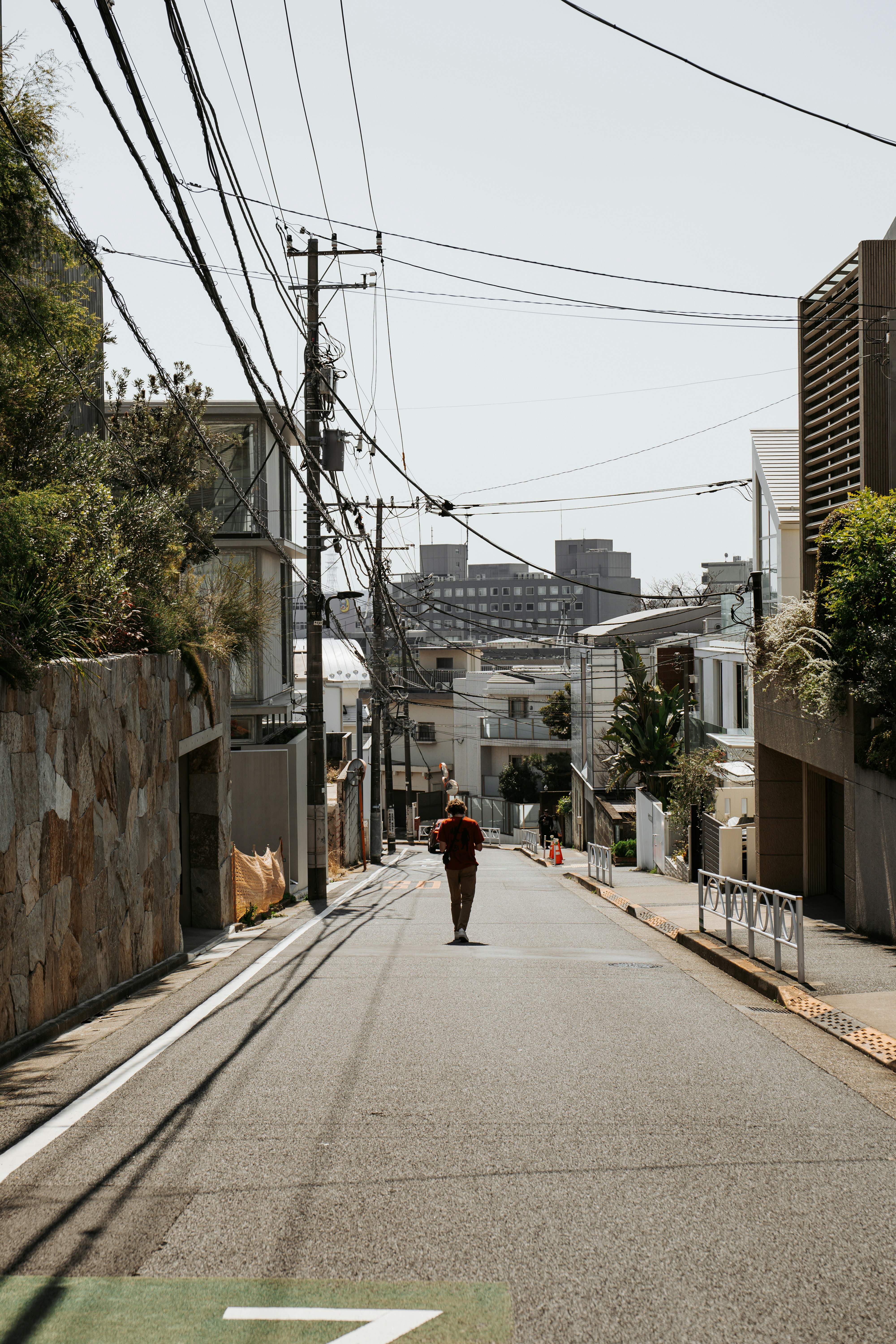 Man walks down a sunny street in a city.