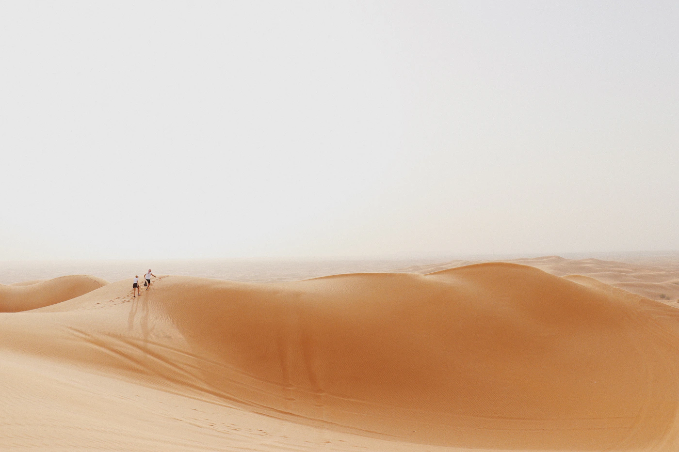 Travellers crossing a vast sand dune in the Dubai desert