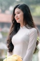 A woman poses gracefully in a white dress.