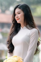 A woman poses gracefully in a white dress.