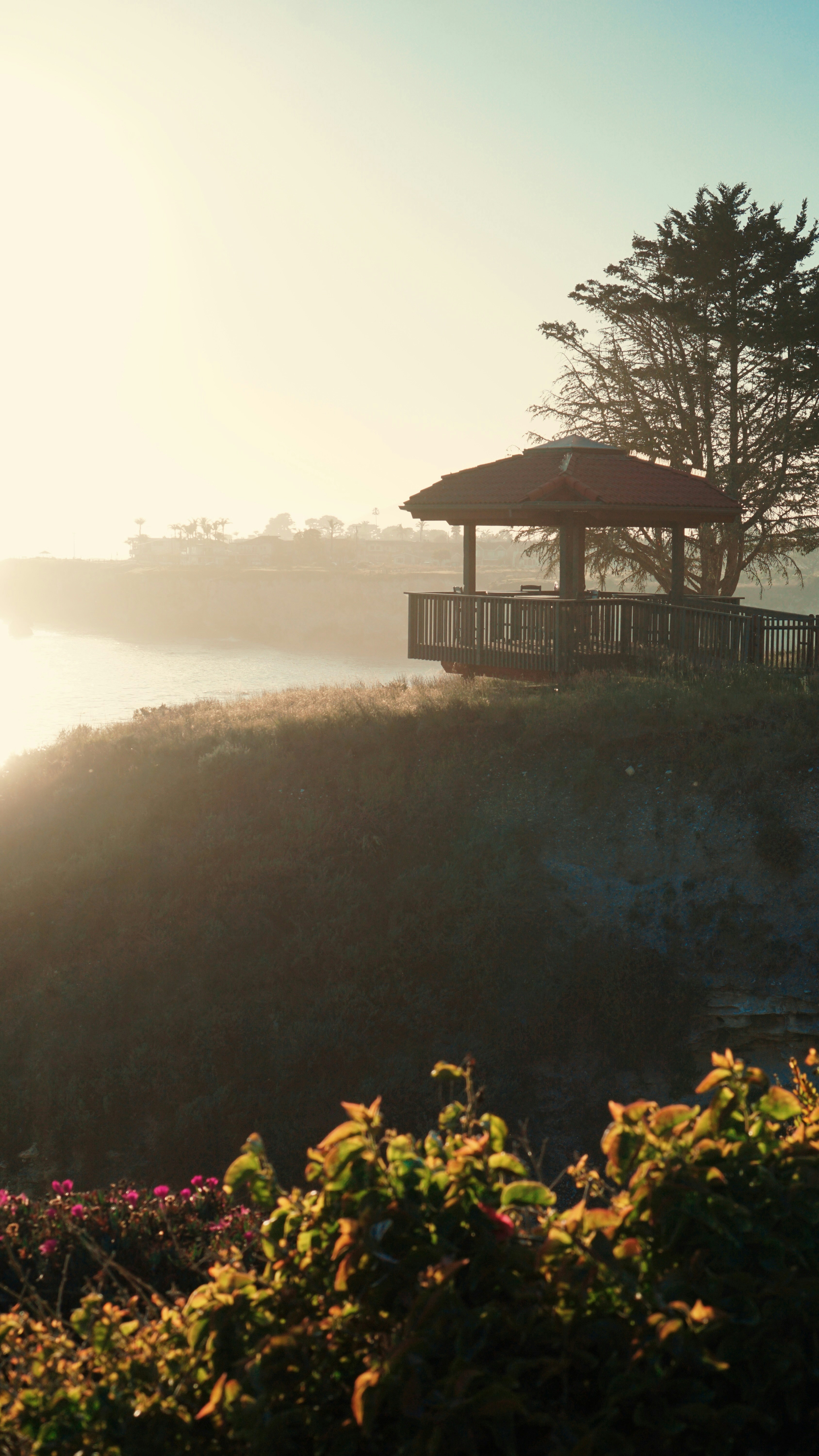 A gazebo overlooks a misty landscape at dawn.
