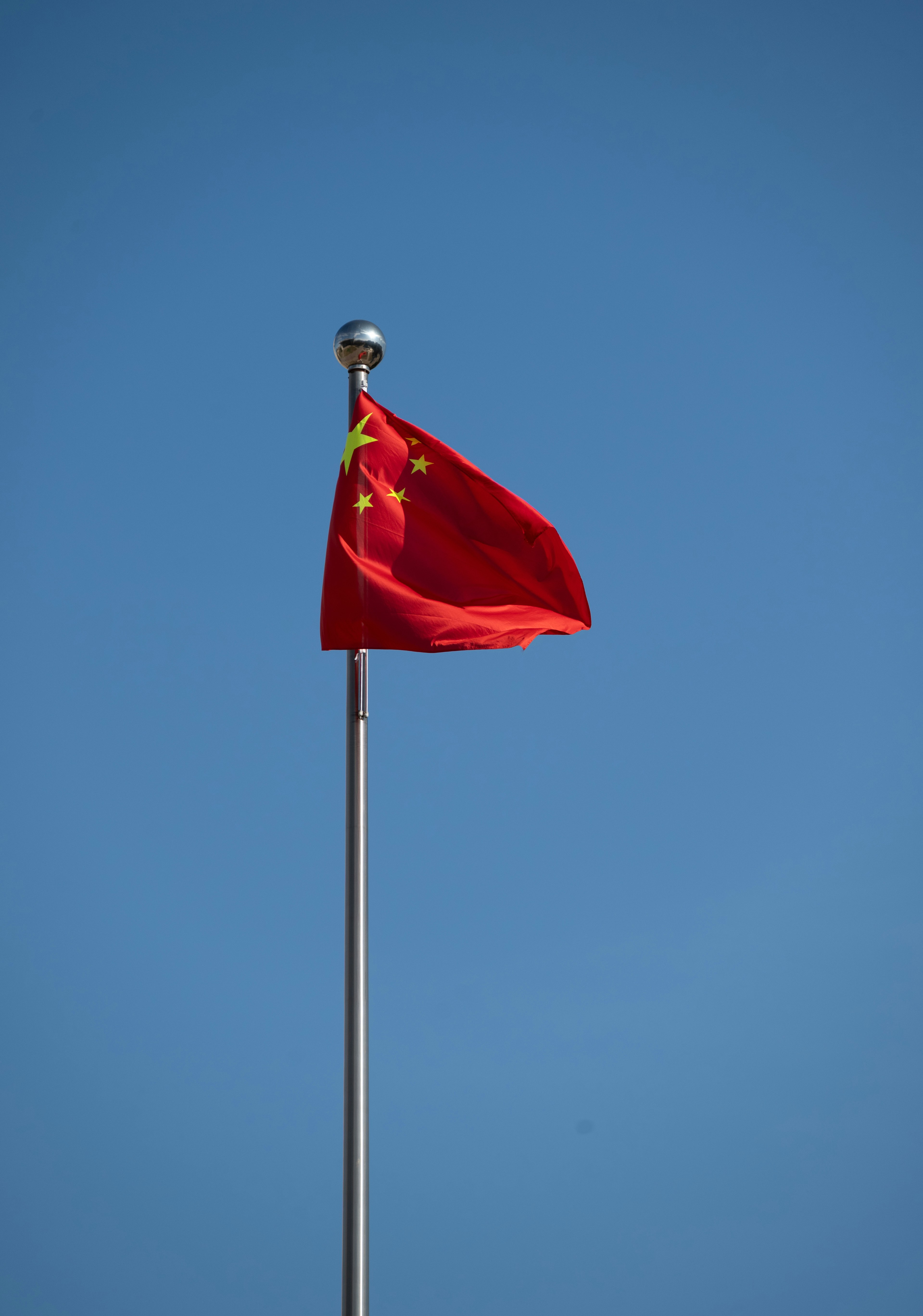 The chinese flag flies proudly against a blue sky.