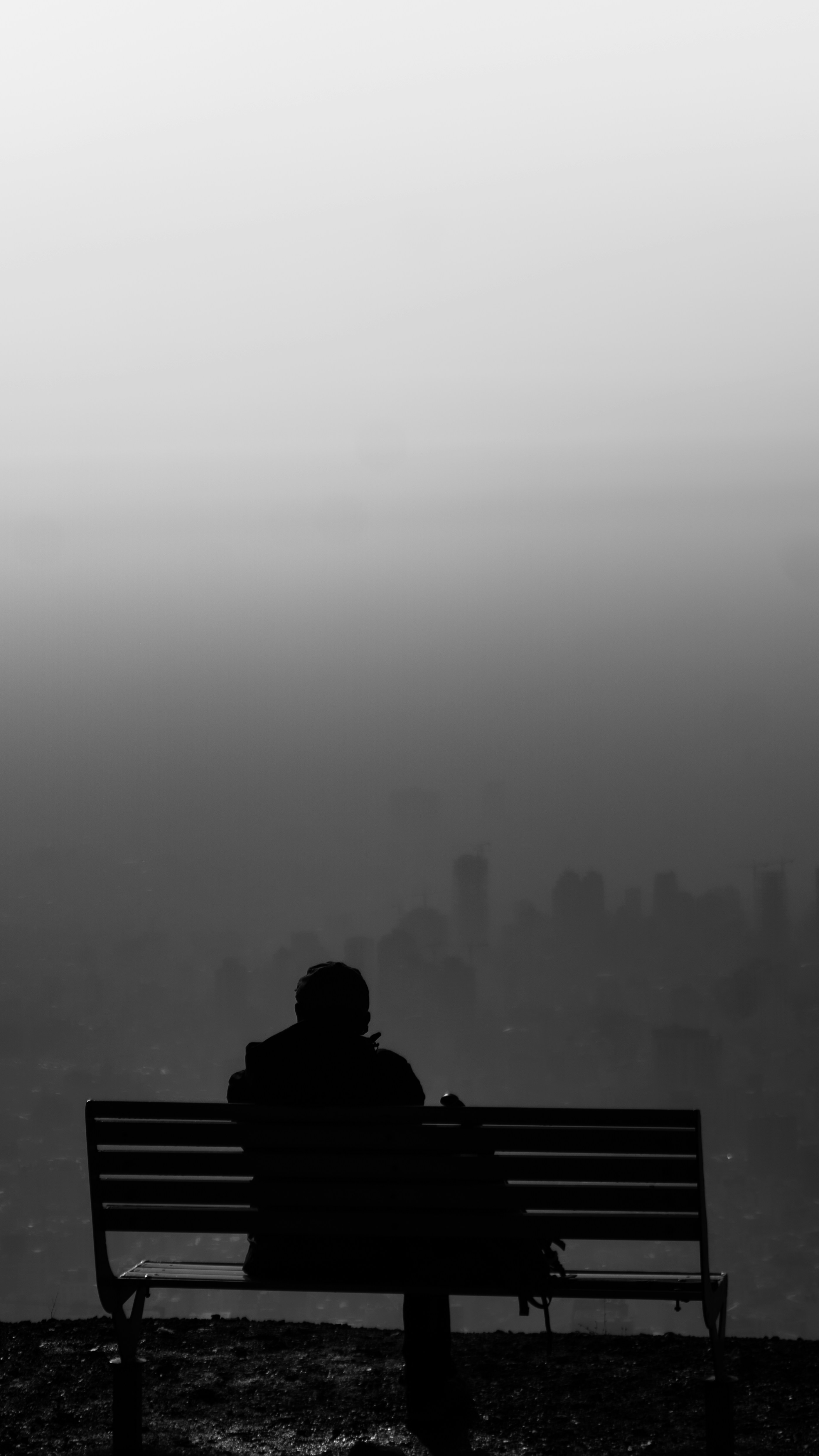 Una persona se sienta en un banco con vistas a un paisaje urbano.