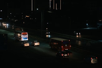 Cars and buses are driving on a highway at night.