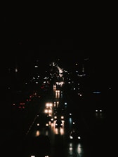 Cars are driving at night on a dark road.