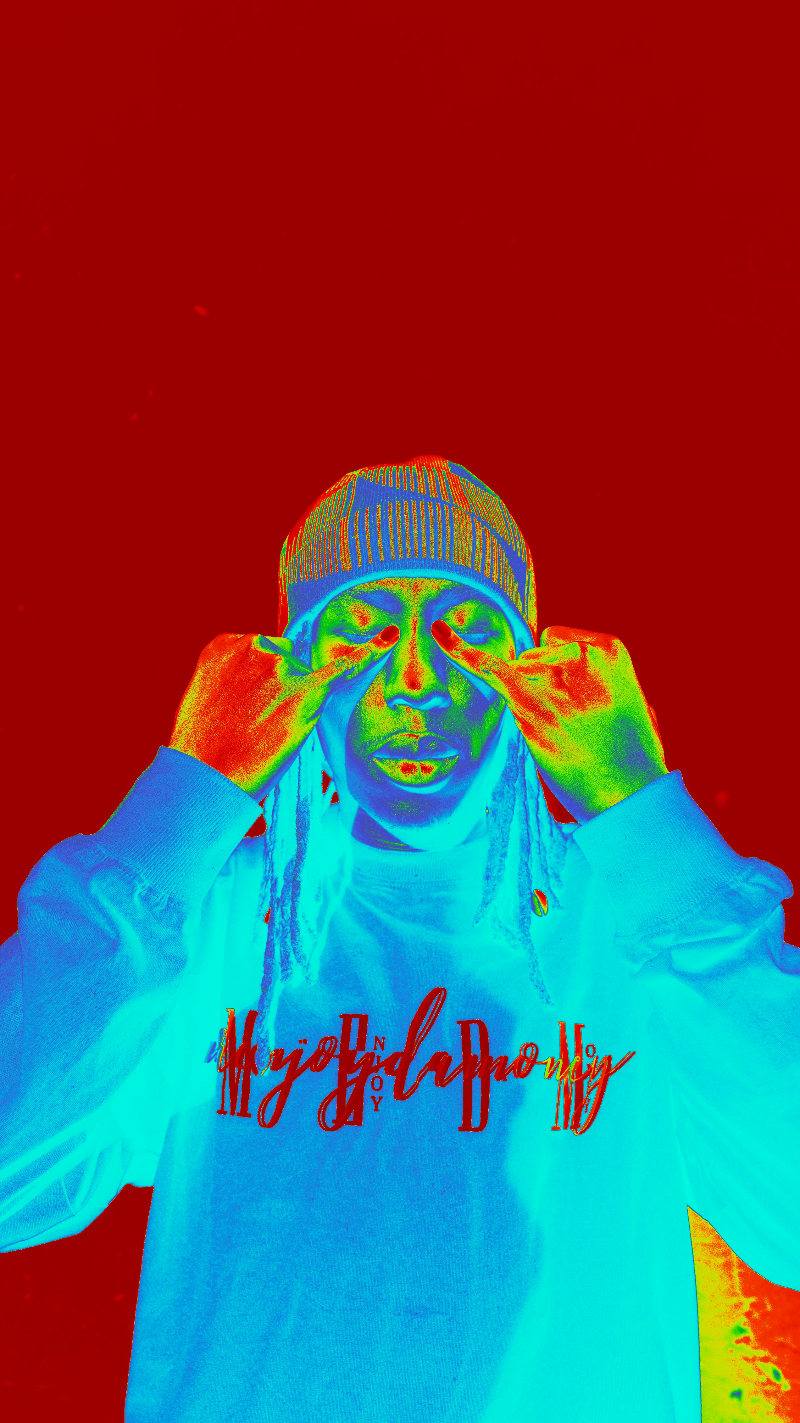 A person wearing a beanie with fingers near eyes.