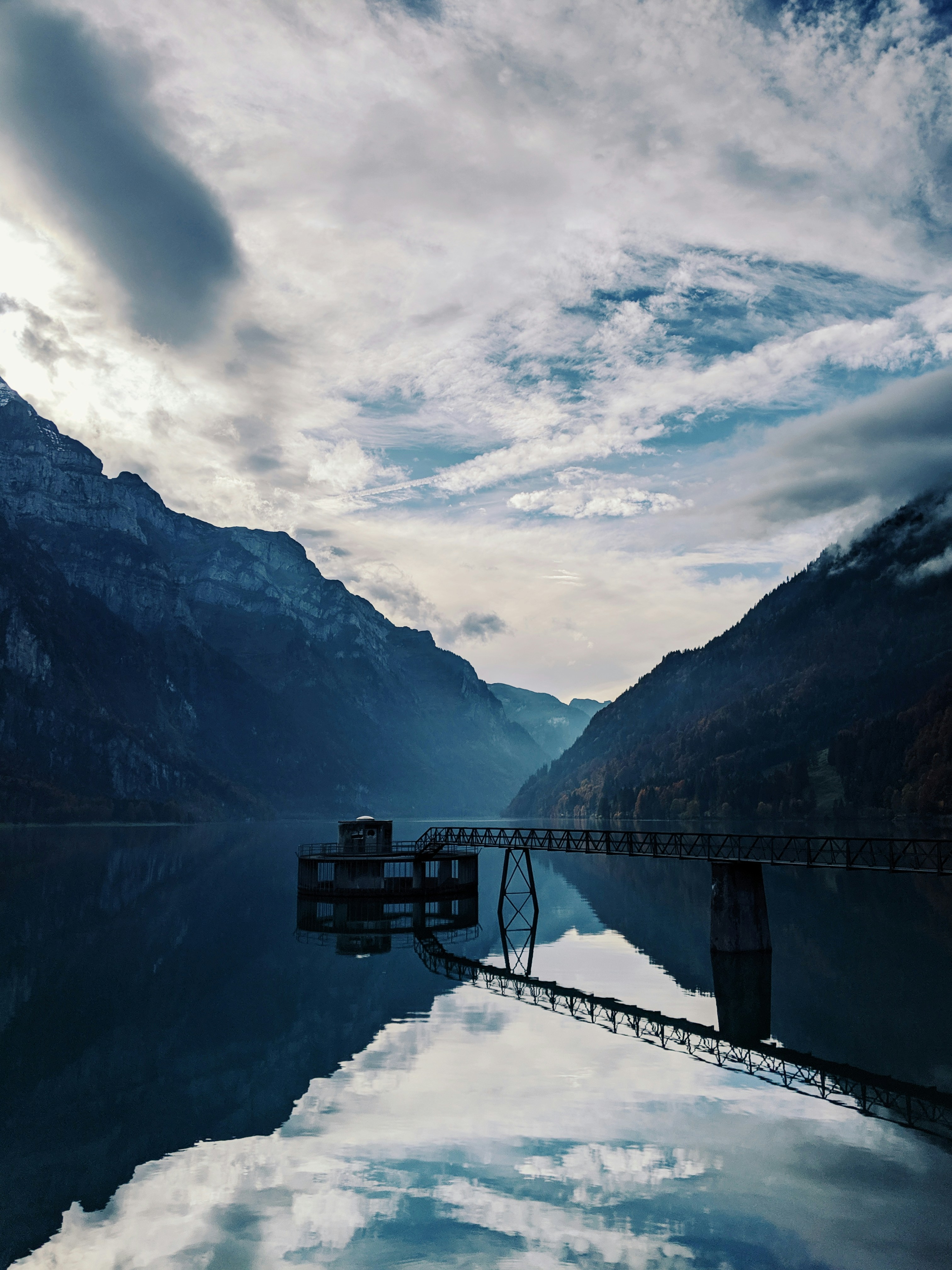 Mountains and cloudy sky reflected in the serene water.