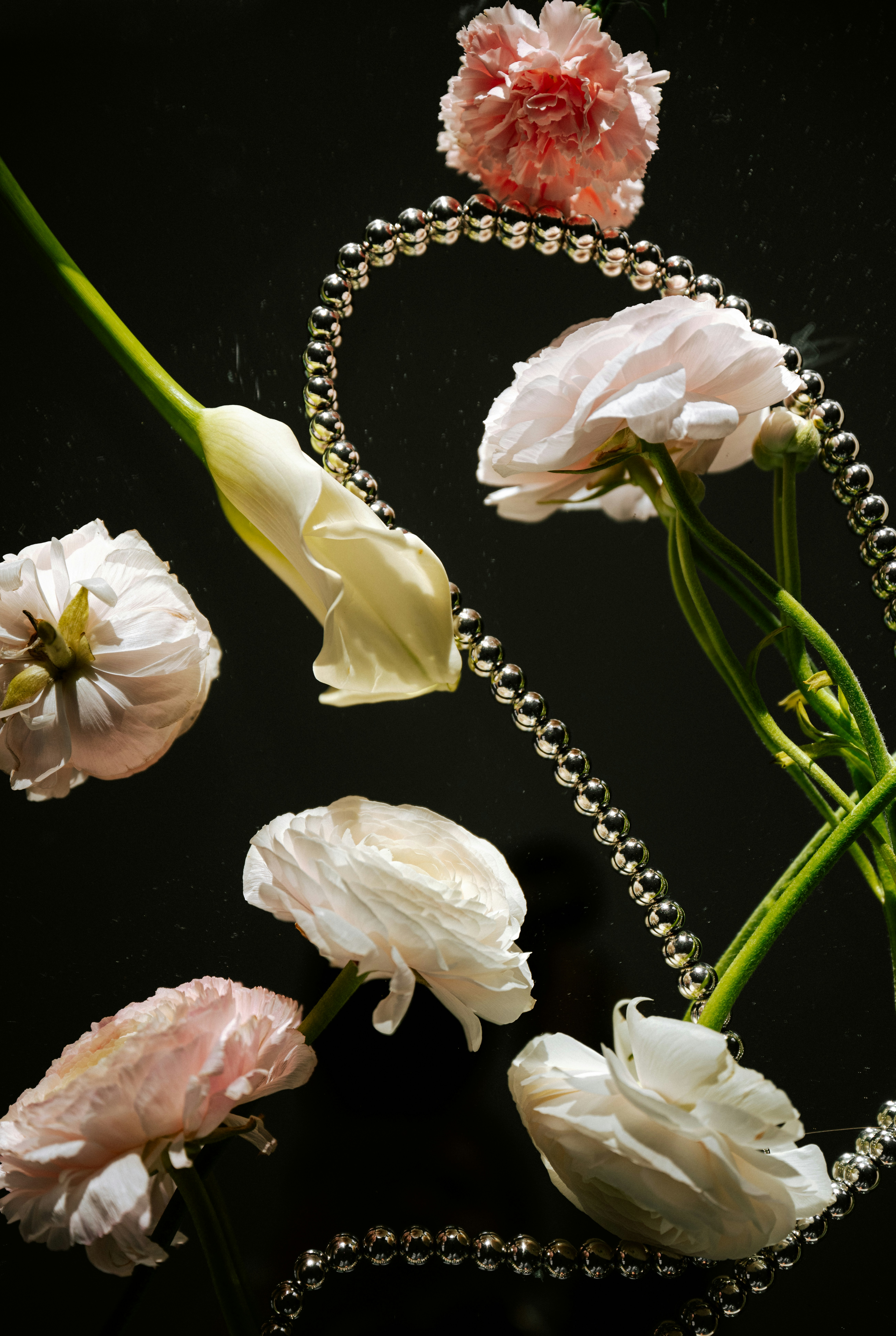 Flowers and pearls float gracefully against a black background.