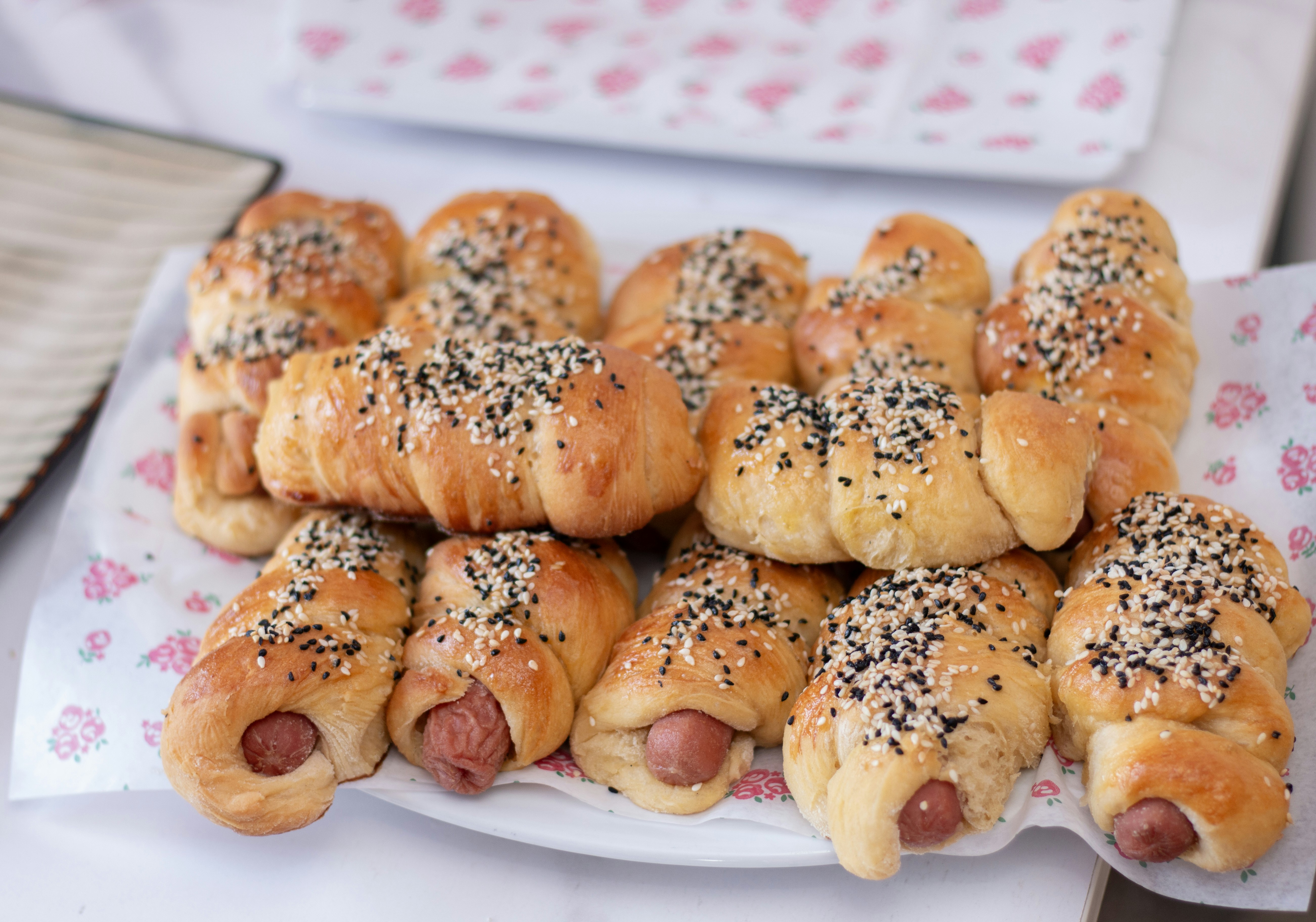 Sausage rolls, garnished with seeds, are beautifully arranged.