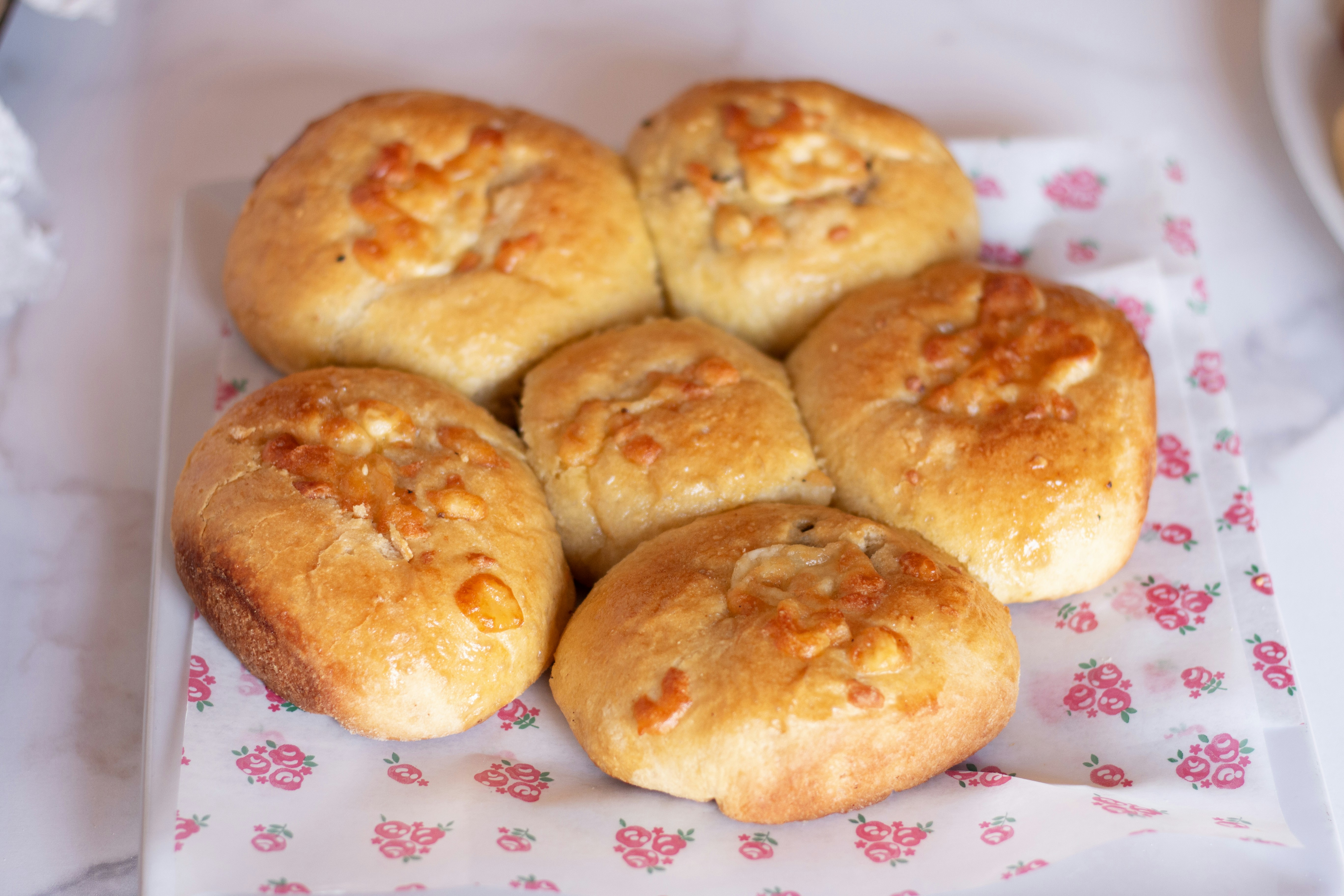 Freshly baked rolls sit on floral paper.