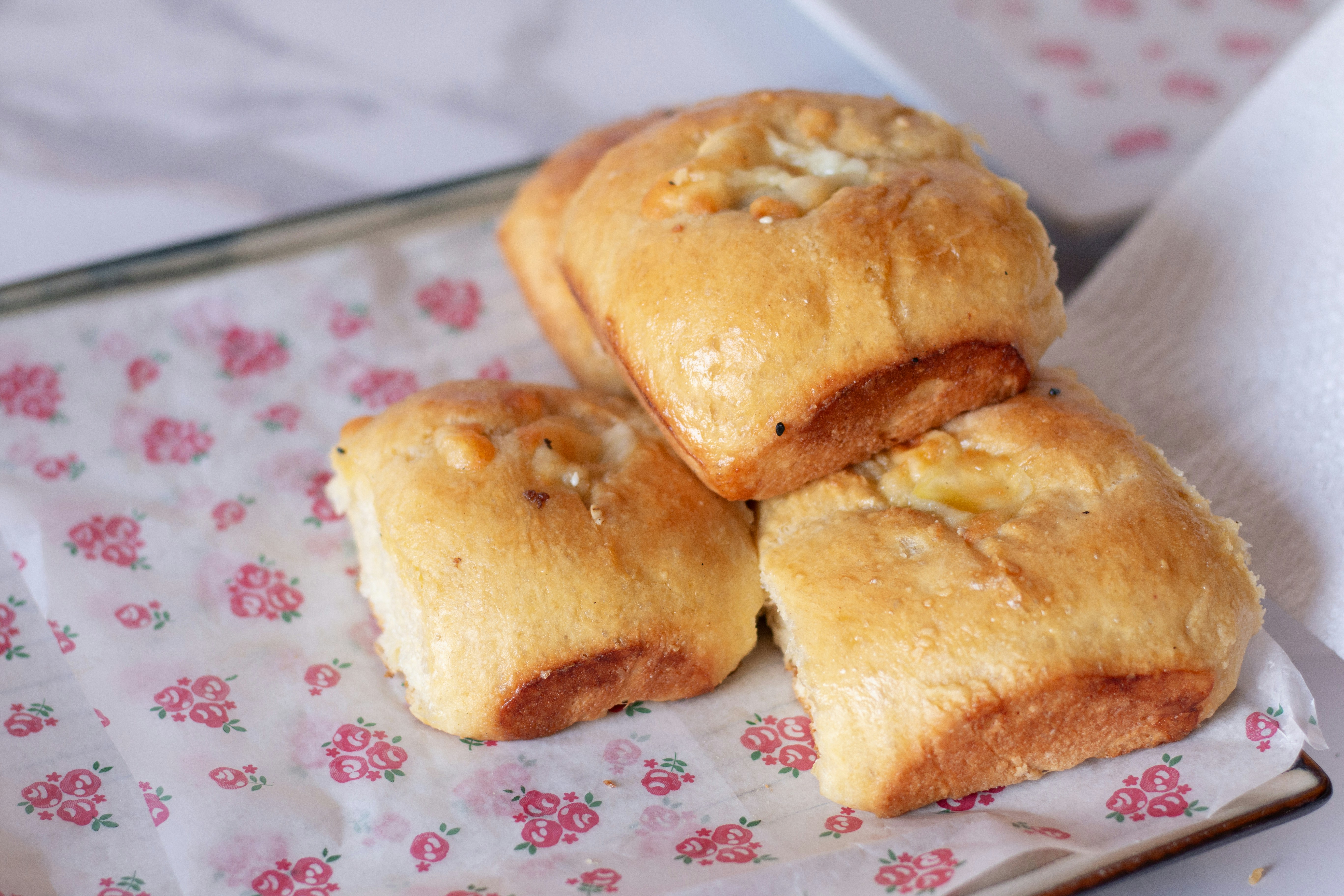 Freshly baked rolls sit on a flowered paper.