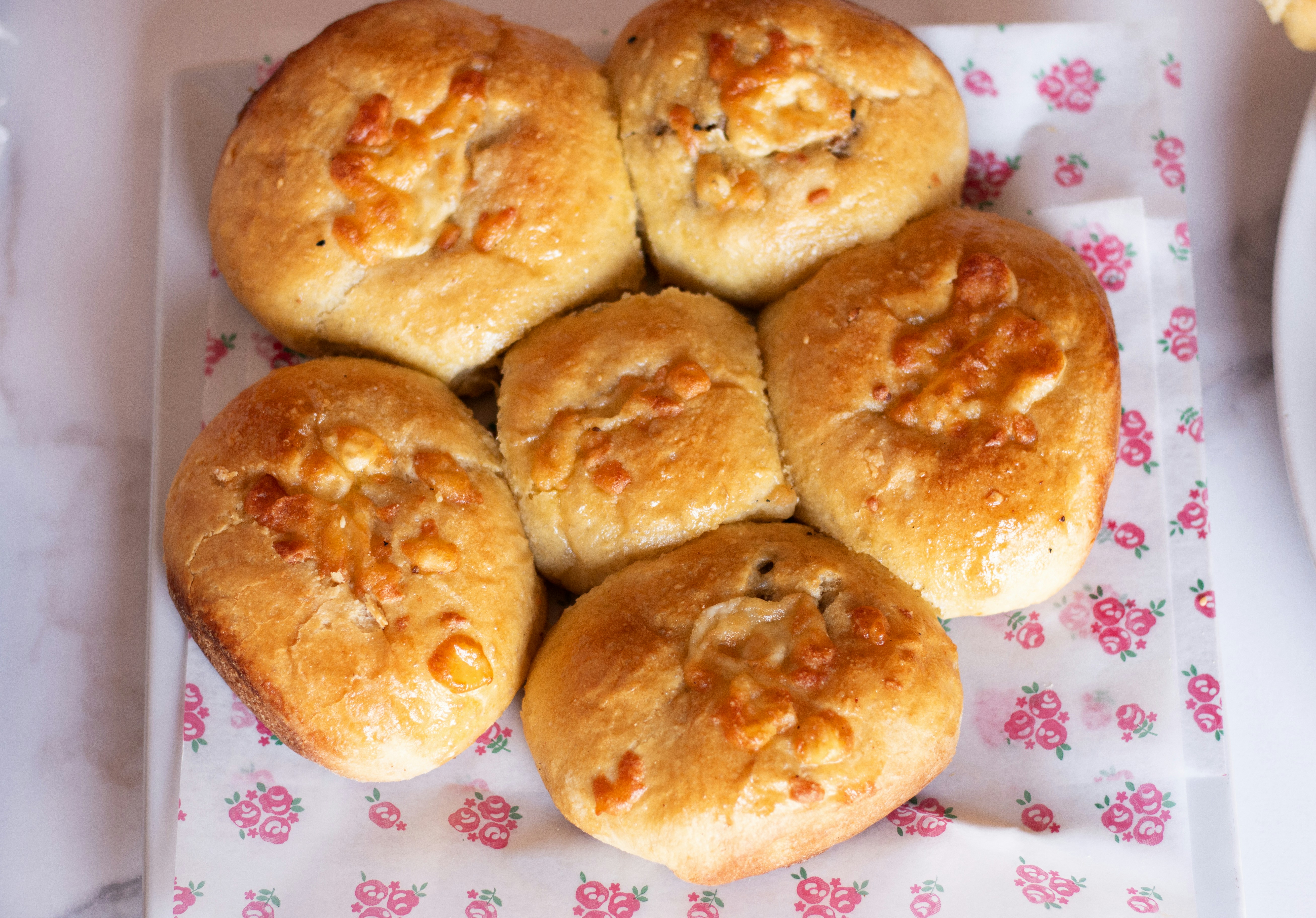 Freshly baked rolls are served on a flowered paper.