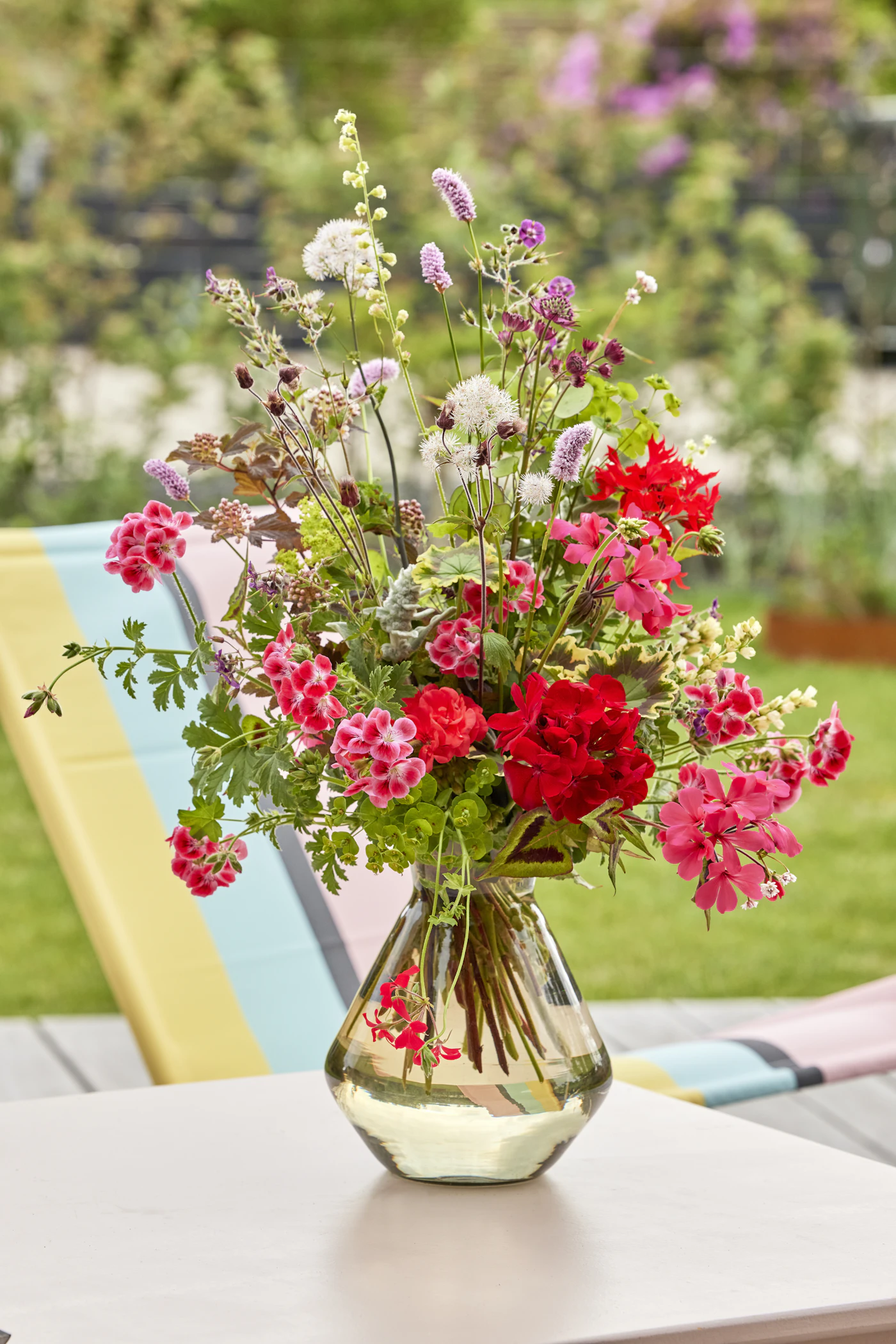 How to make your own wedding centerpieces — A completed, elegant DIY wedding centerpiece made with white roses and greenery on a guest table.