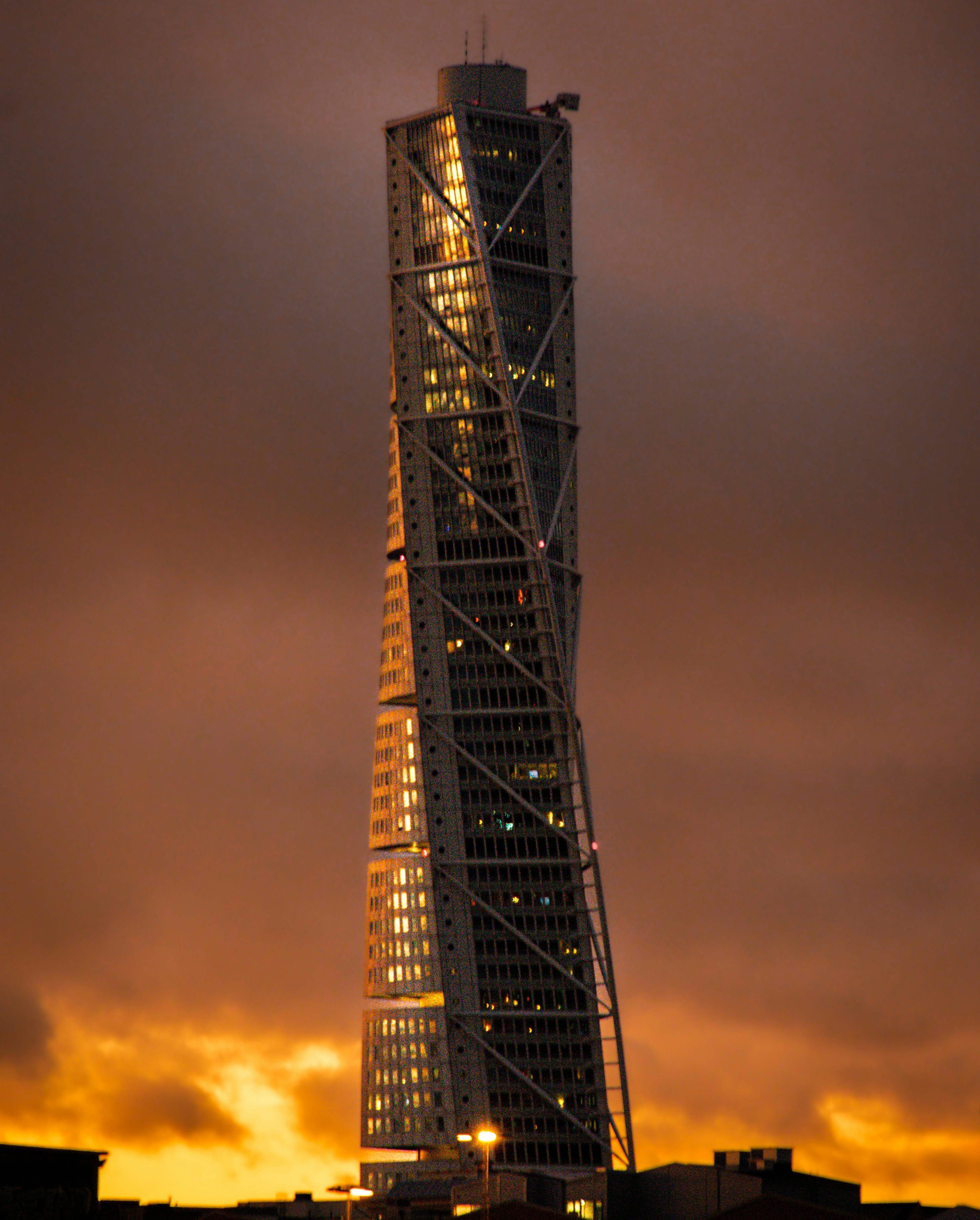 The turning torso skyscraper illuminated against a sunset.