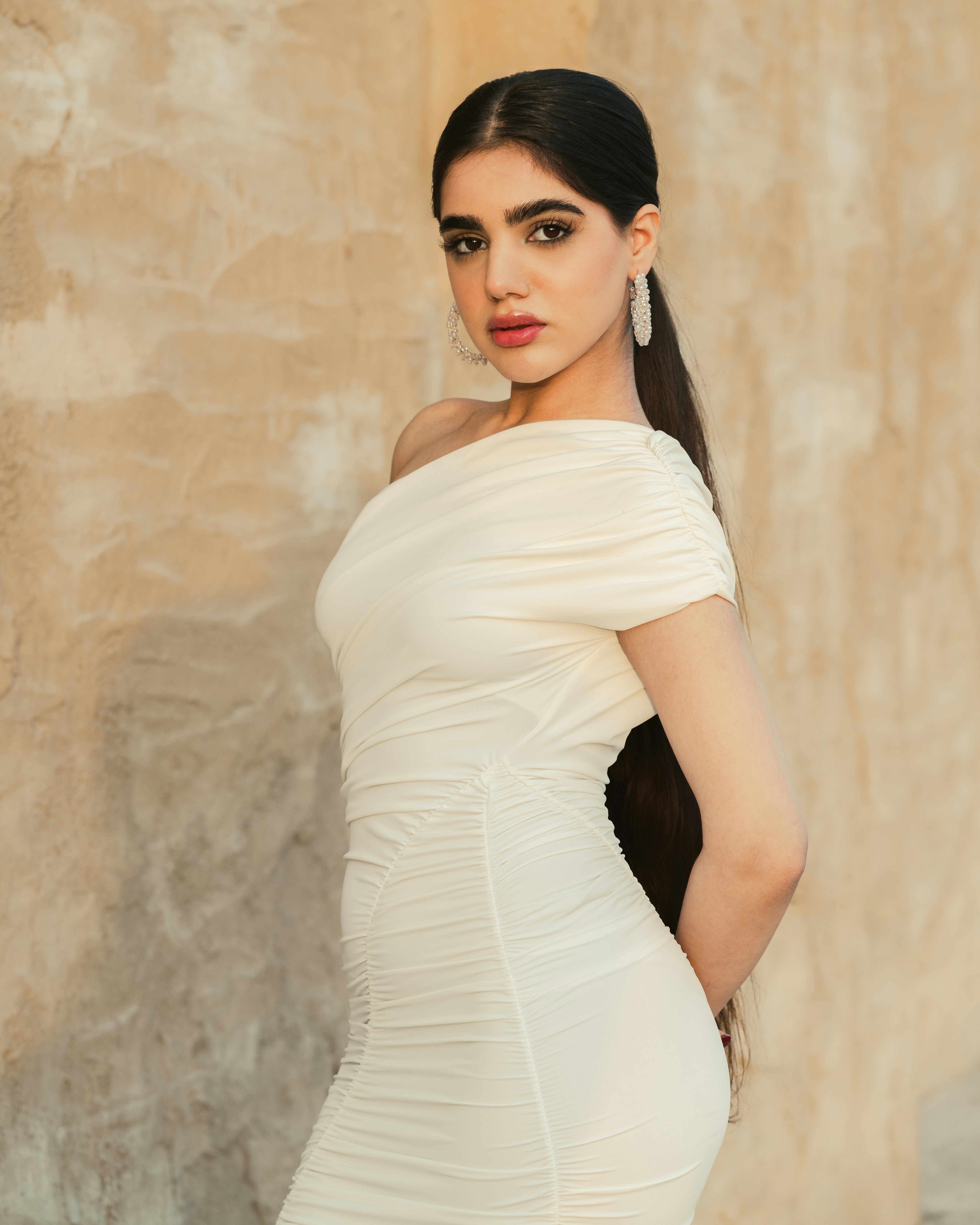 Eine Frau posiert in einem cremefarbenen Kleid.