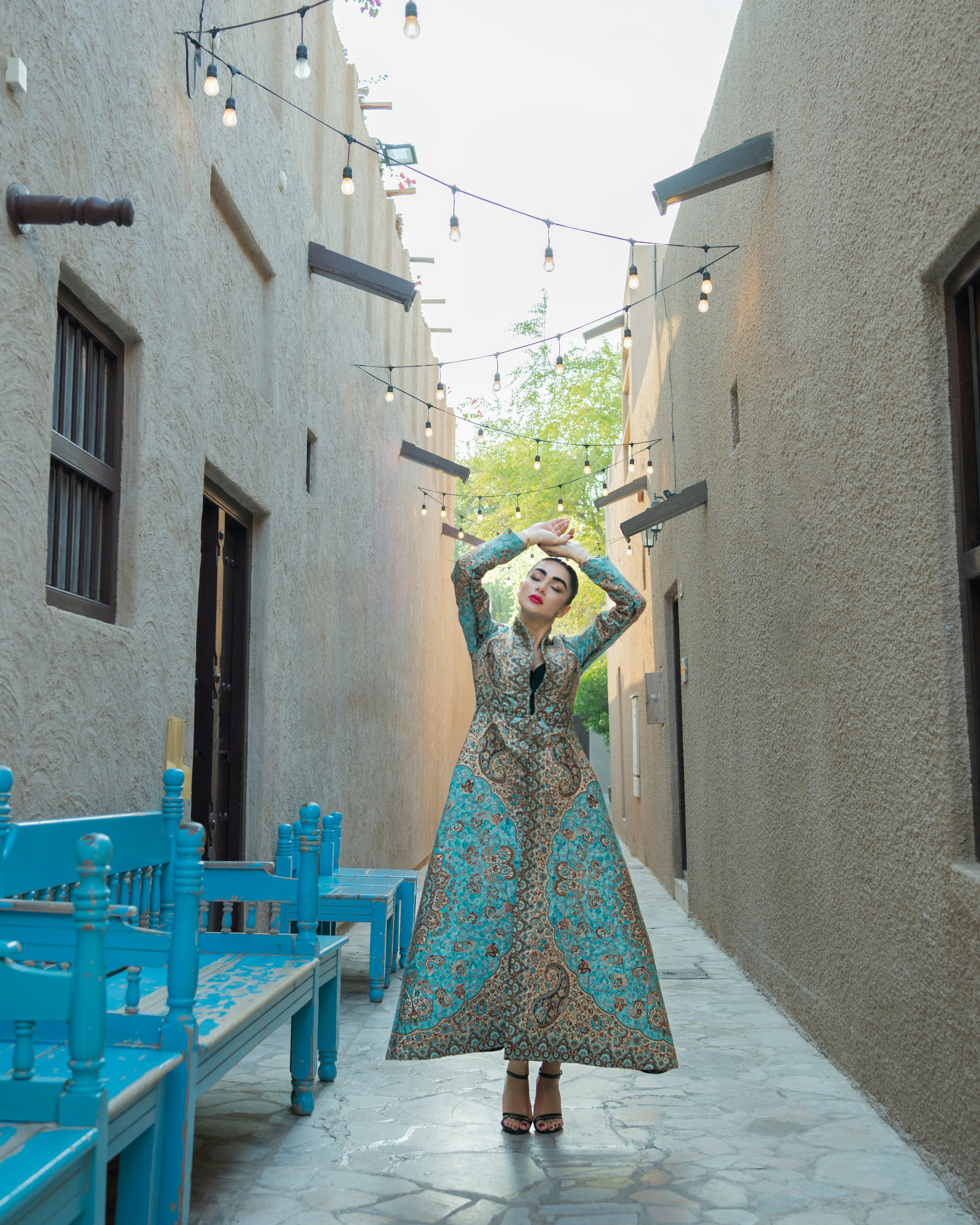 Mujer con vestido adornado posa en el callejón.