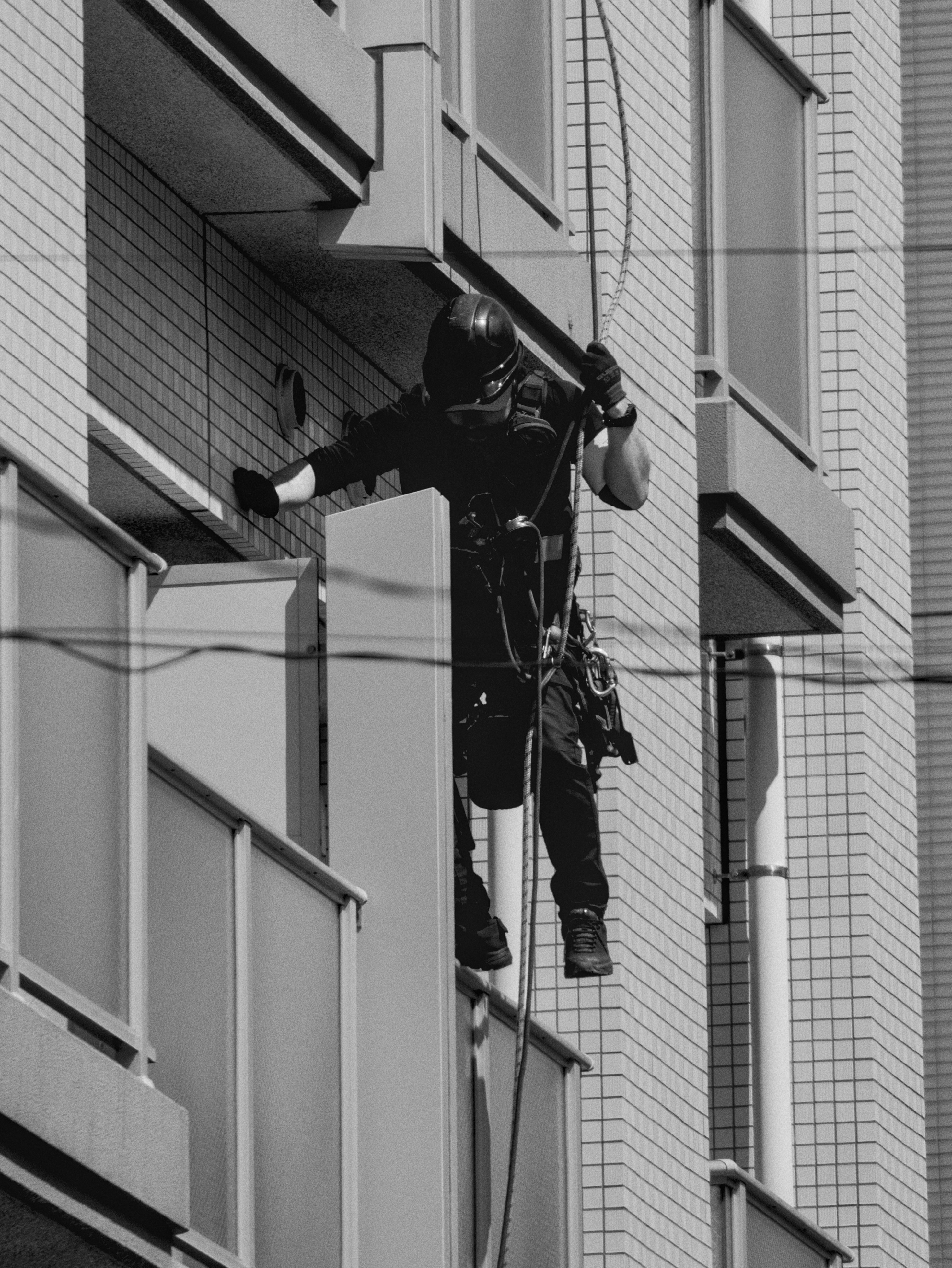 Una persona si cala in corda doppia lungo il lato di un edificio.