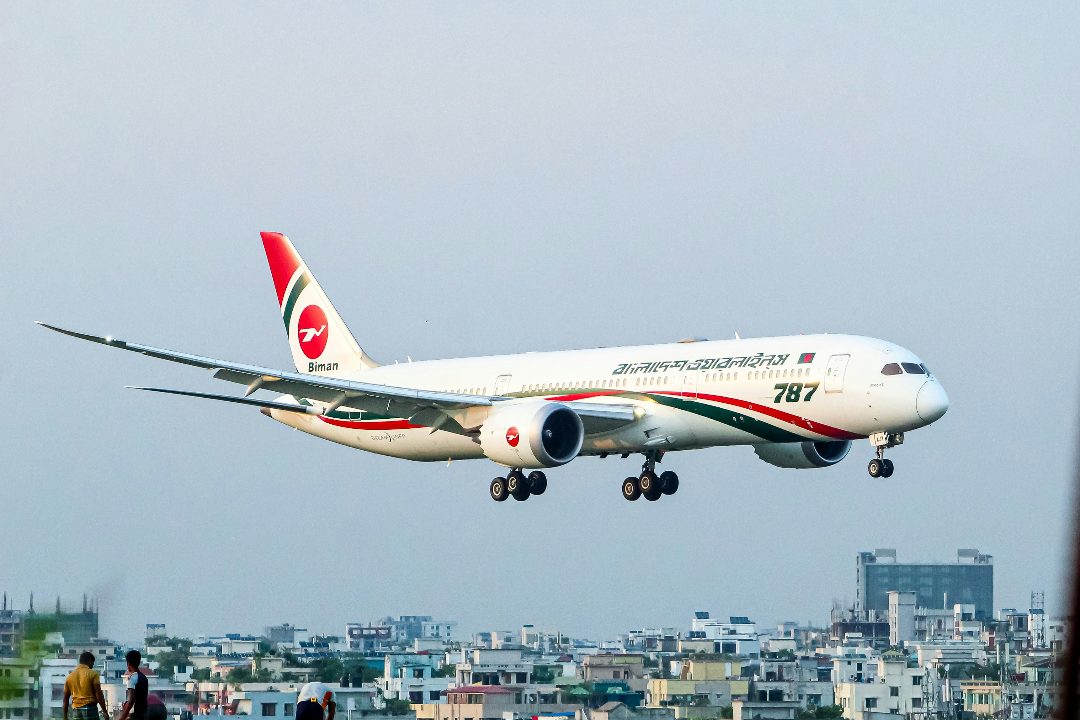 An airplane is landing over a city.