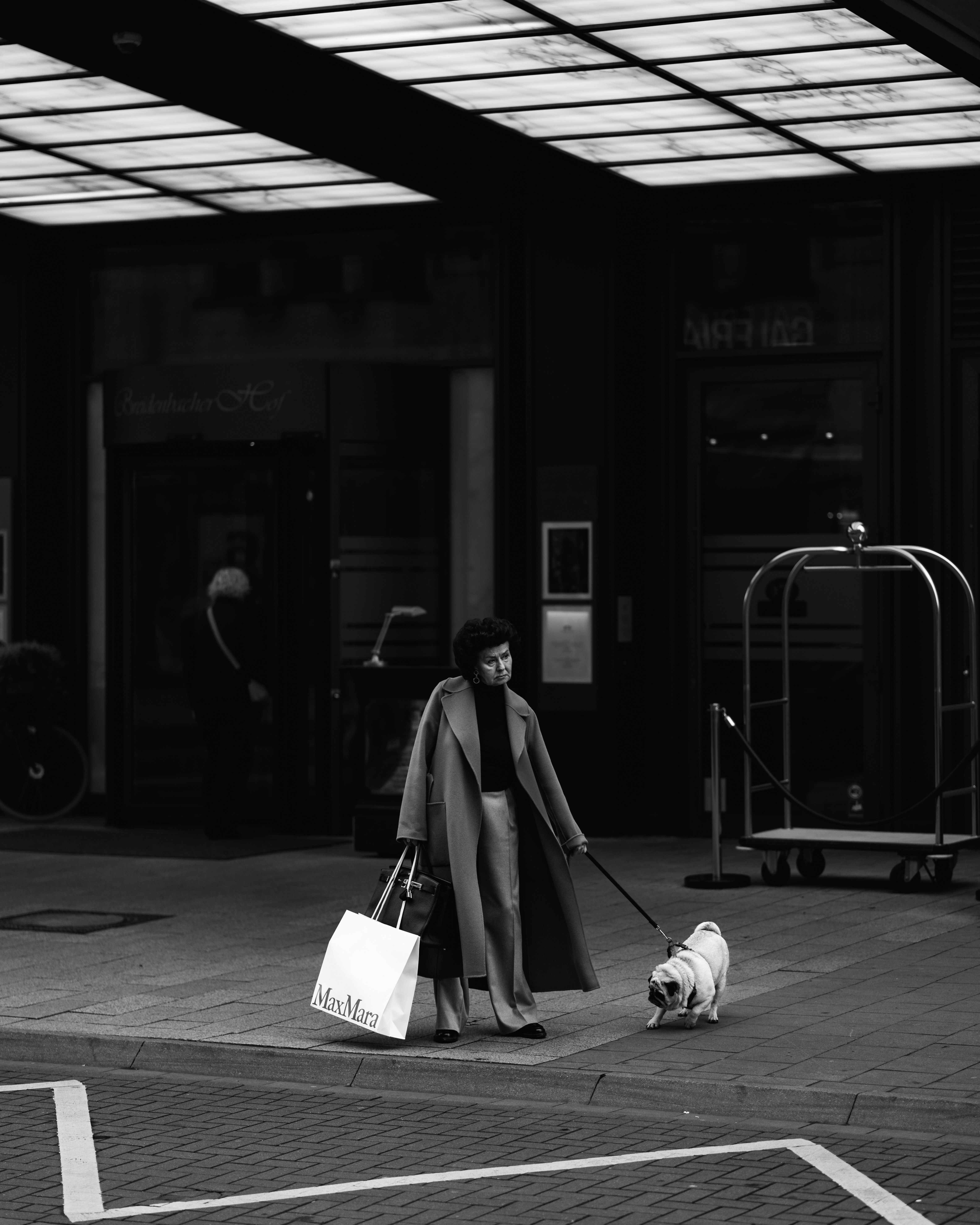 Mulher passeia com seu pug do lado de fora de um prédio.
