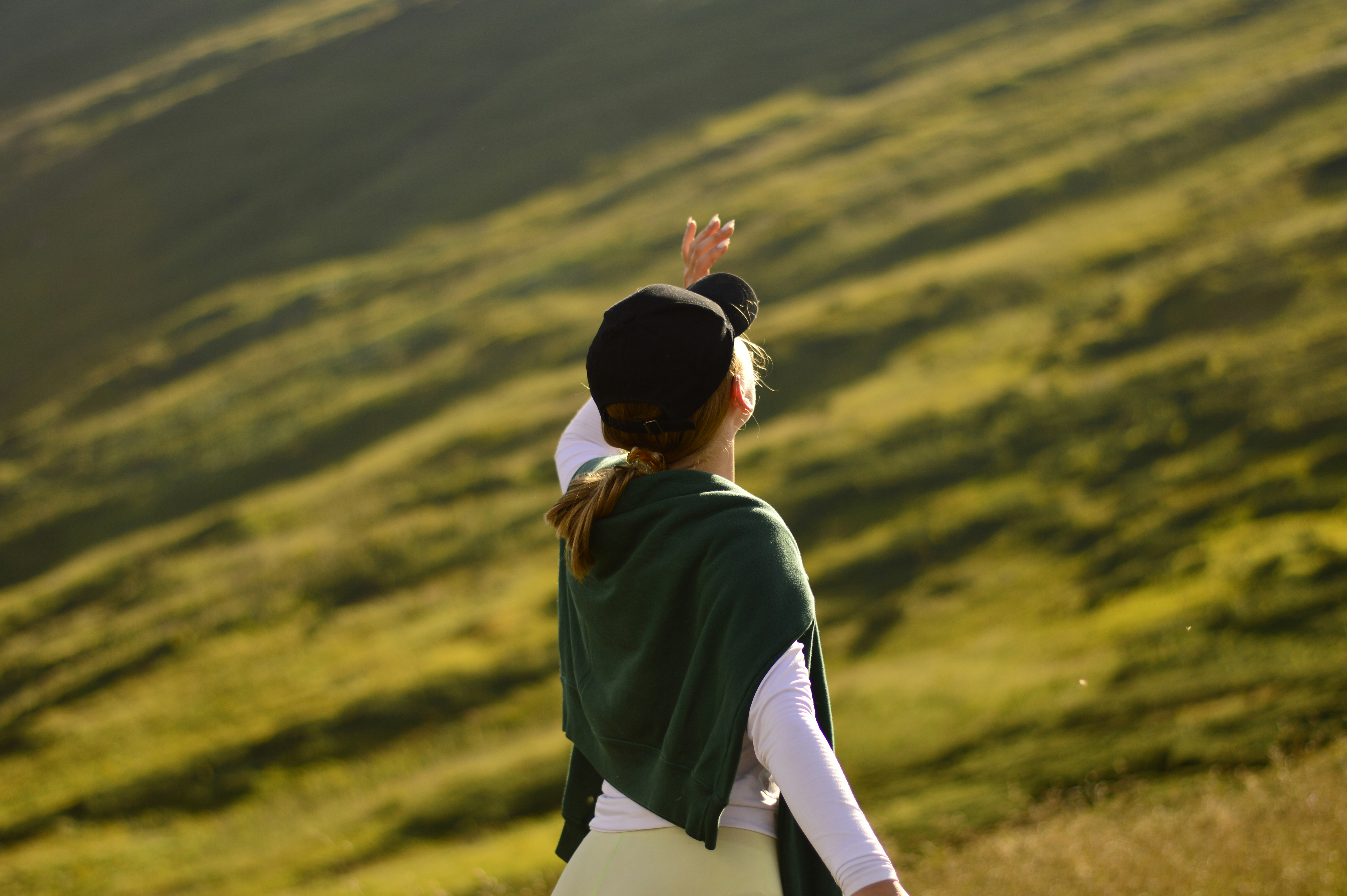 Woman raises hand, looking at the mountain view.