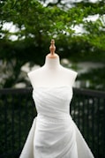 A white wedding dress is displayed on a mannequin.