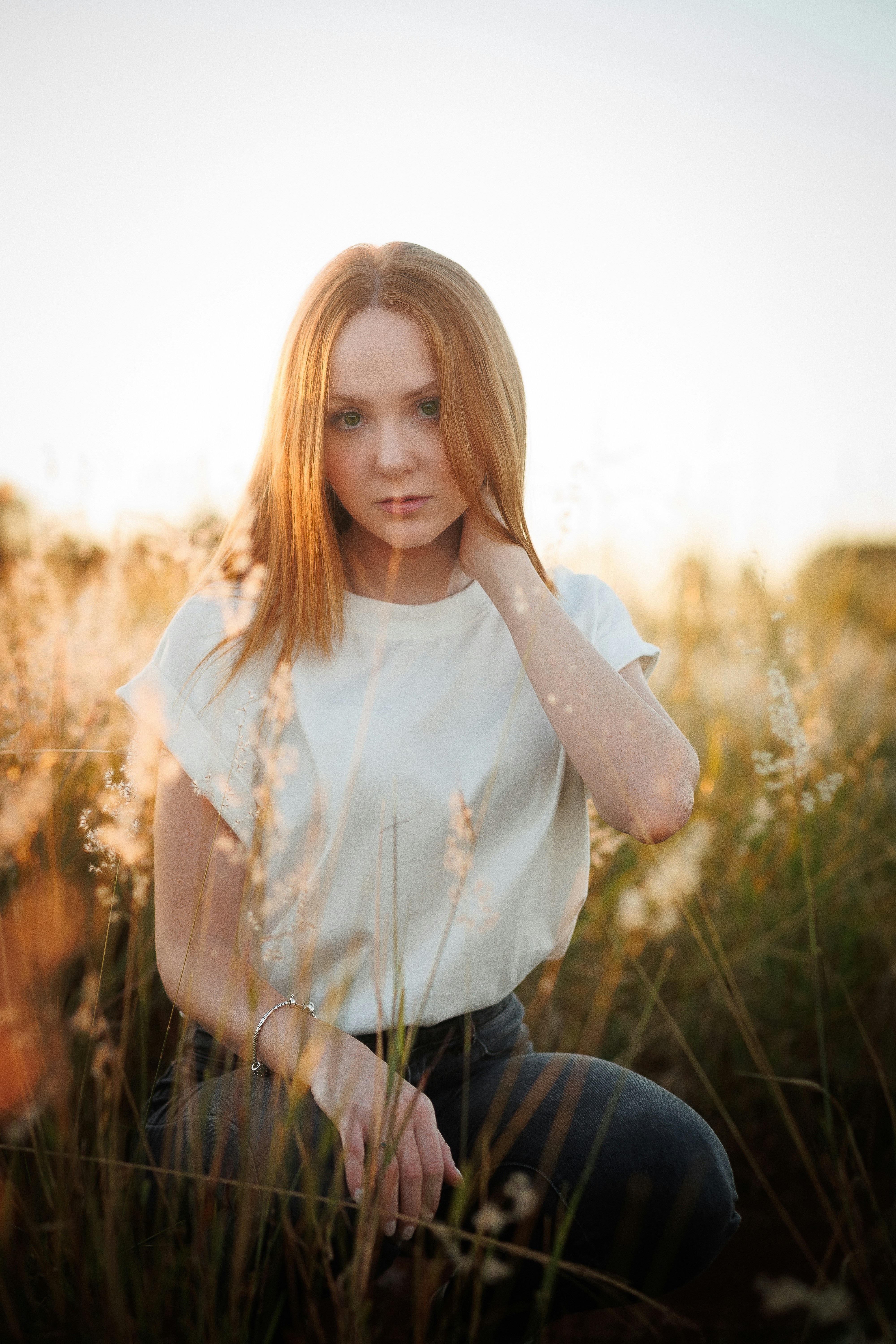 A young woman poses in a field of tall grass.
